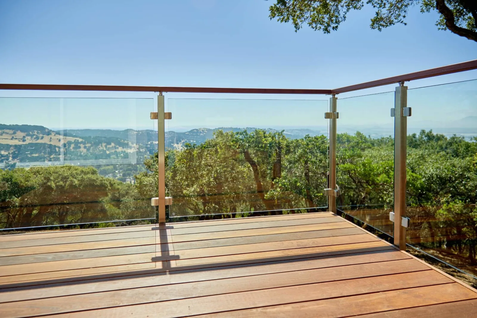 Glass railing wrapping a deck corner above a wooded valley