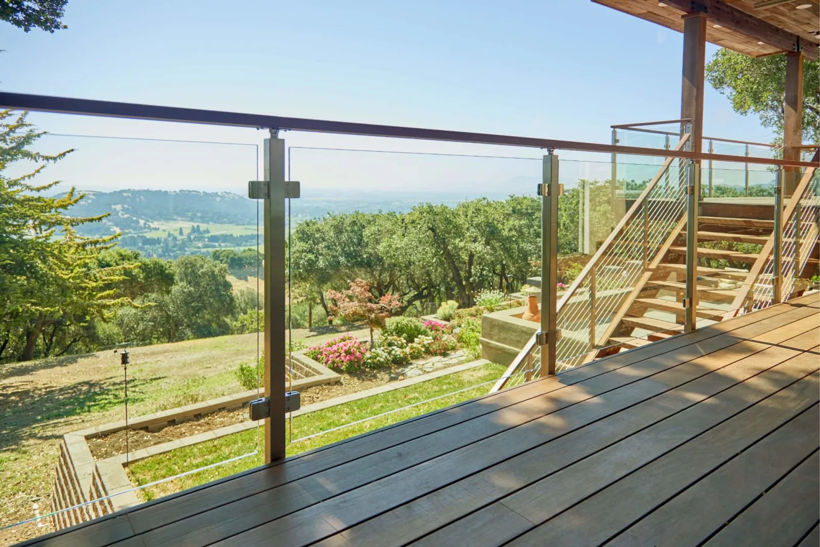 Deck railing of glass panels with a wood top rail overlooking rolling hills