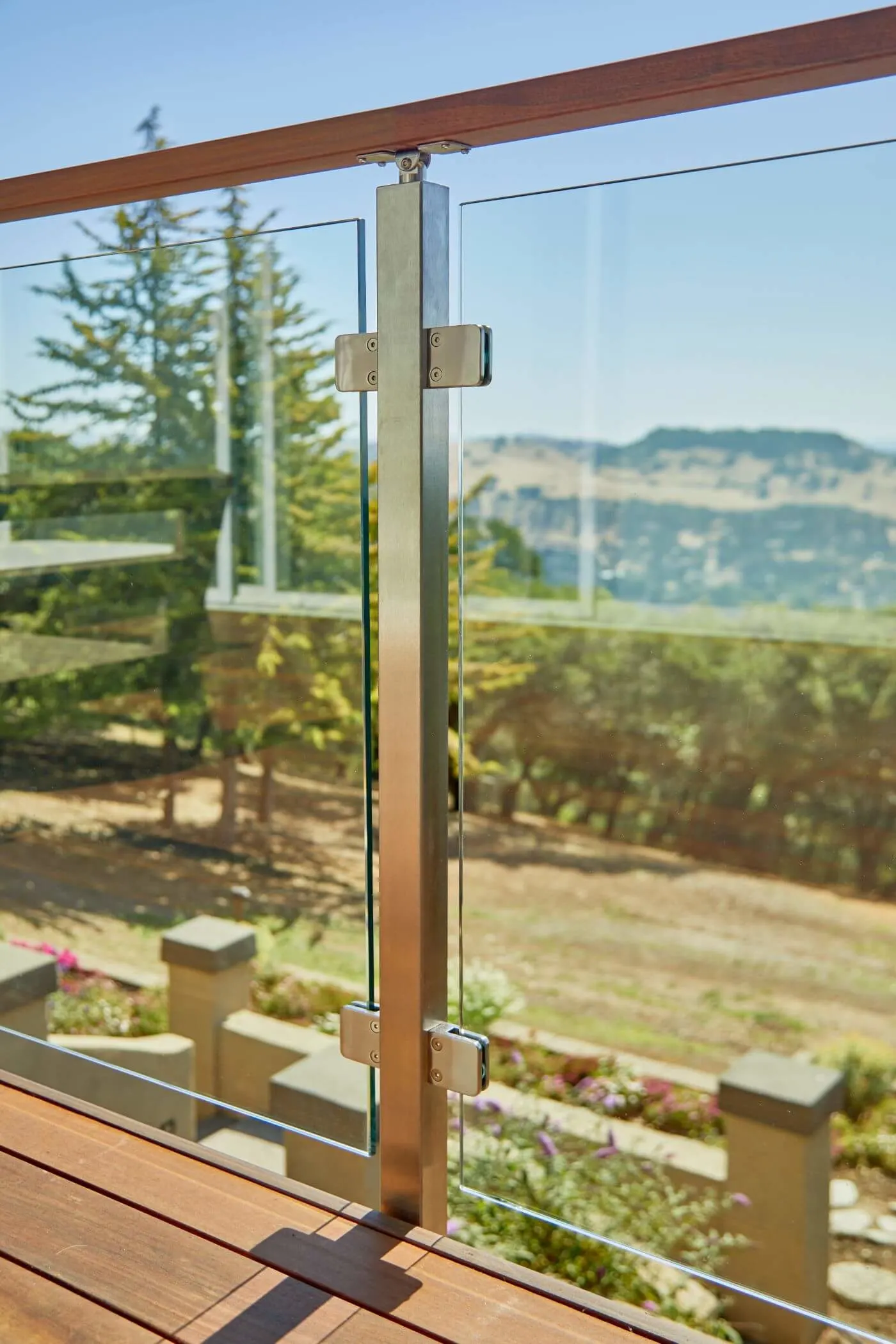 Post clips holding glass panels on a deck above a ridge