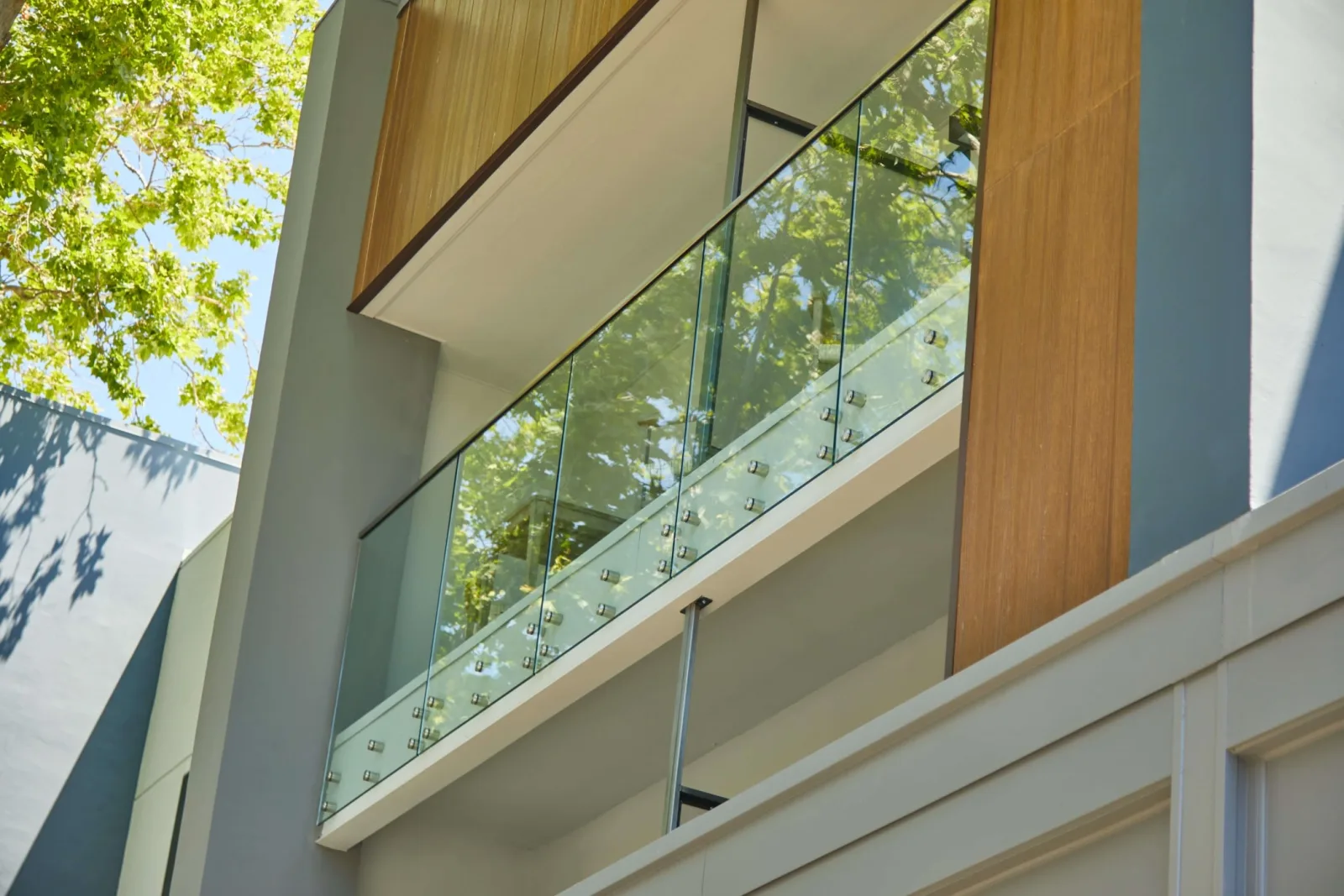 Looking up at a balcony where standoff pins hold the glass panels