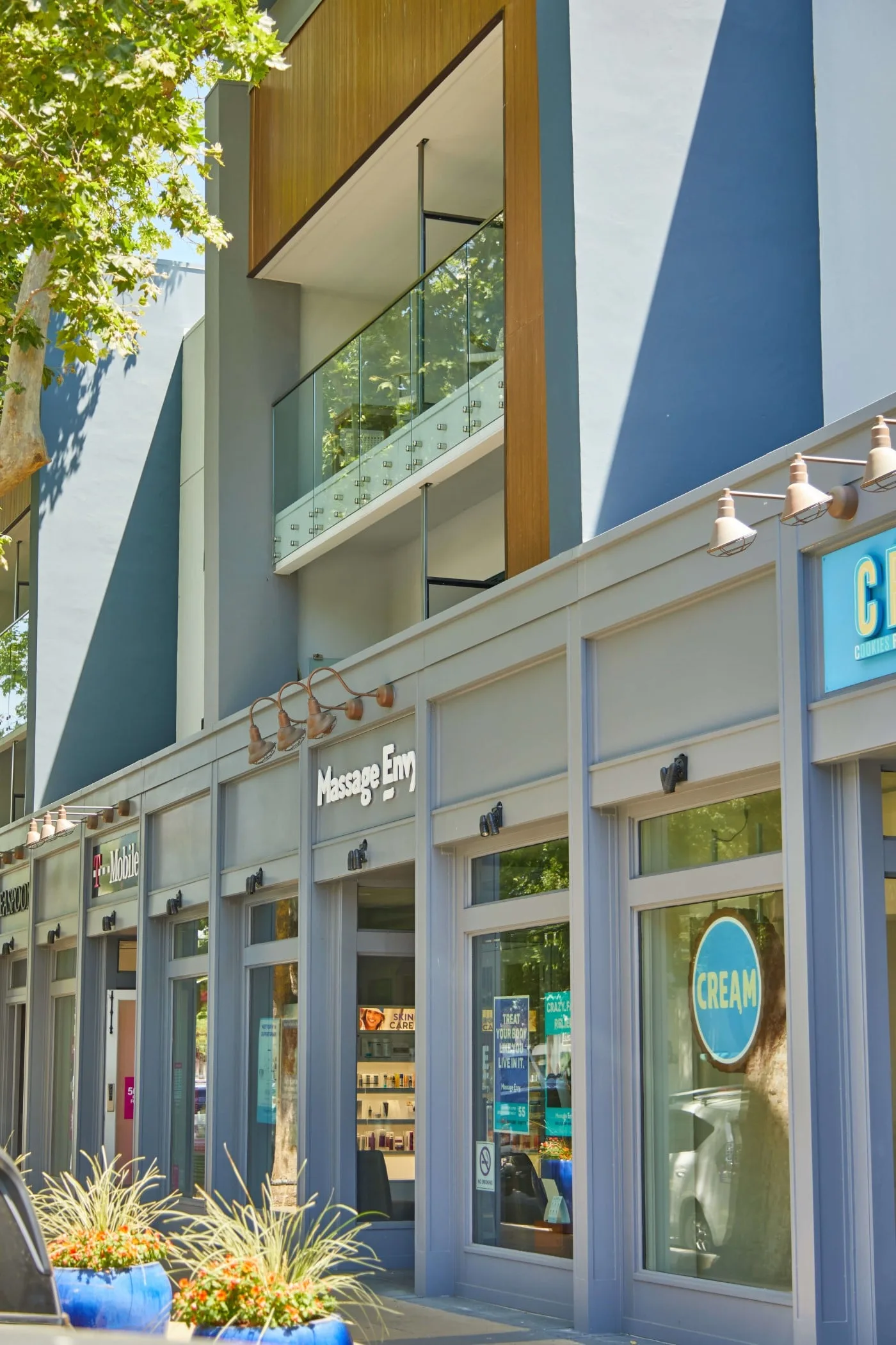 Street-level storefronts below a recessed balcony fitted with glass railing