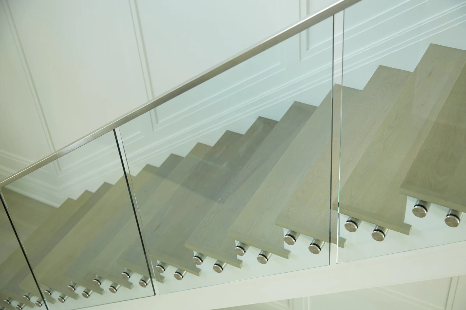Stair stringer and treads seen through glass held by round standoffs
