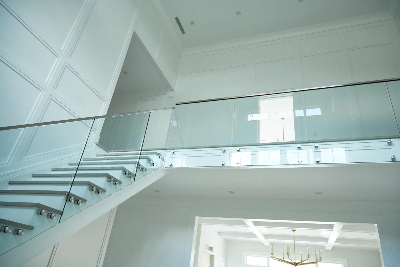 Balcony railing spanning a double-height space with a chandelier below