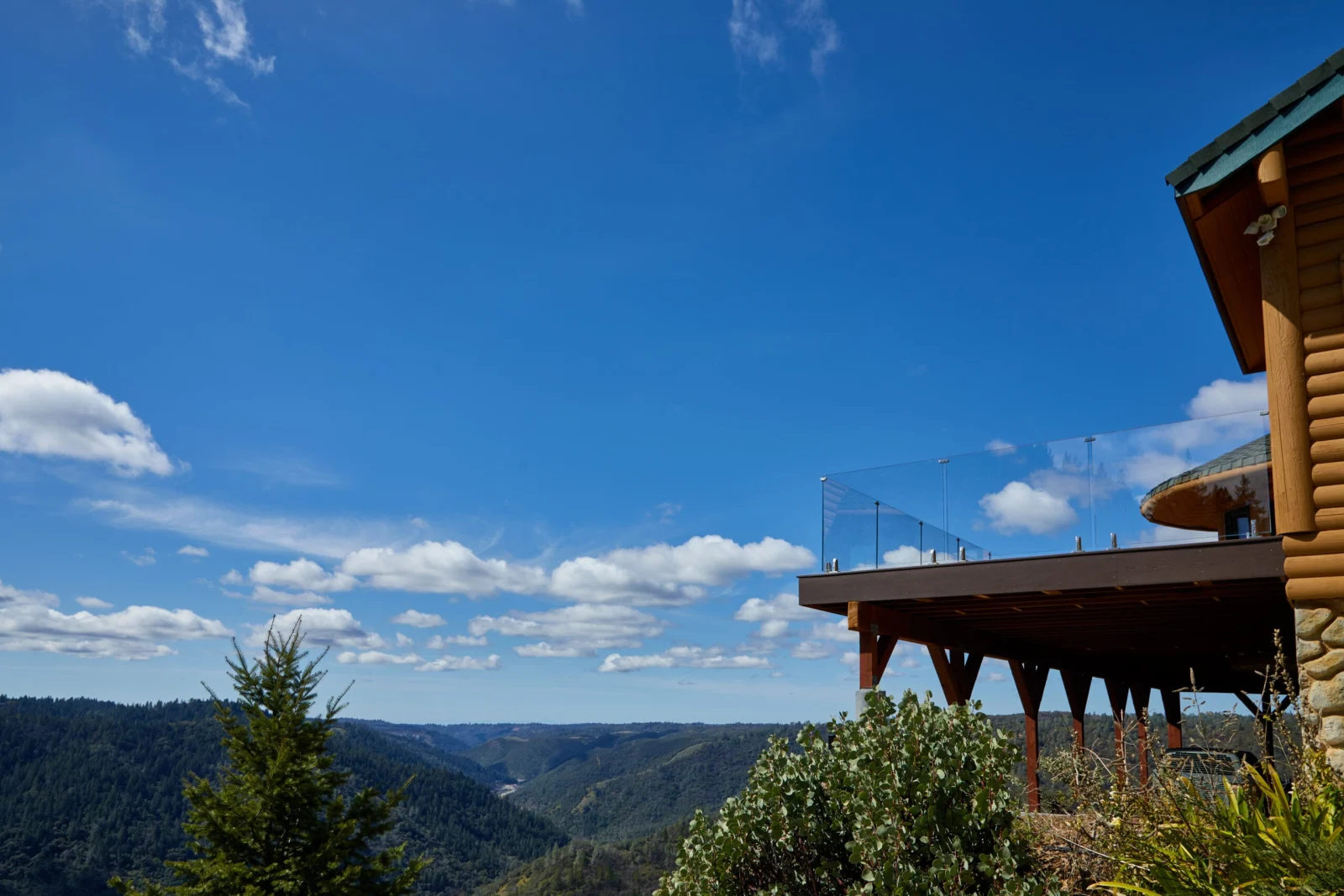 Hillside home with its glass-railed deck seen from across the valley
