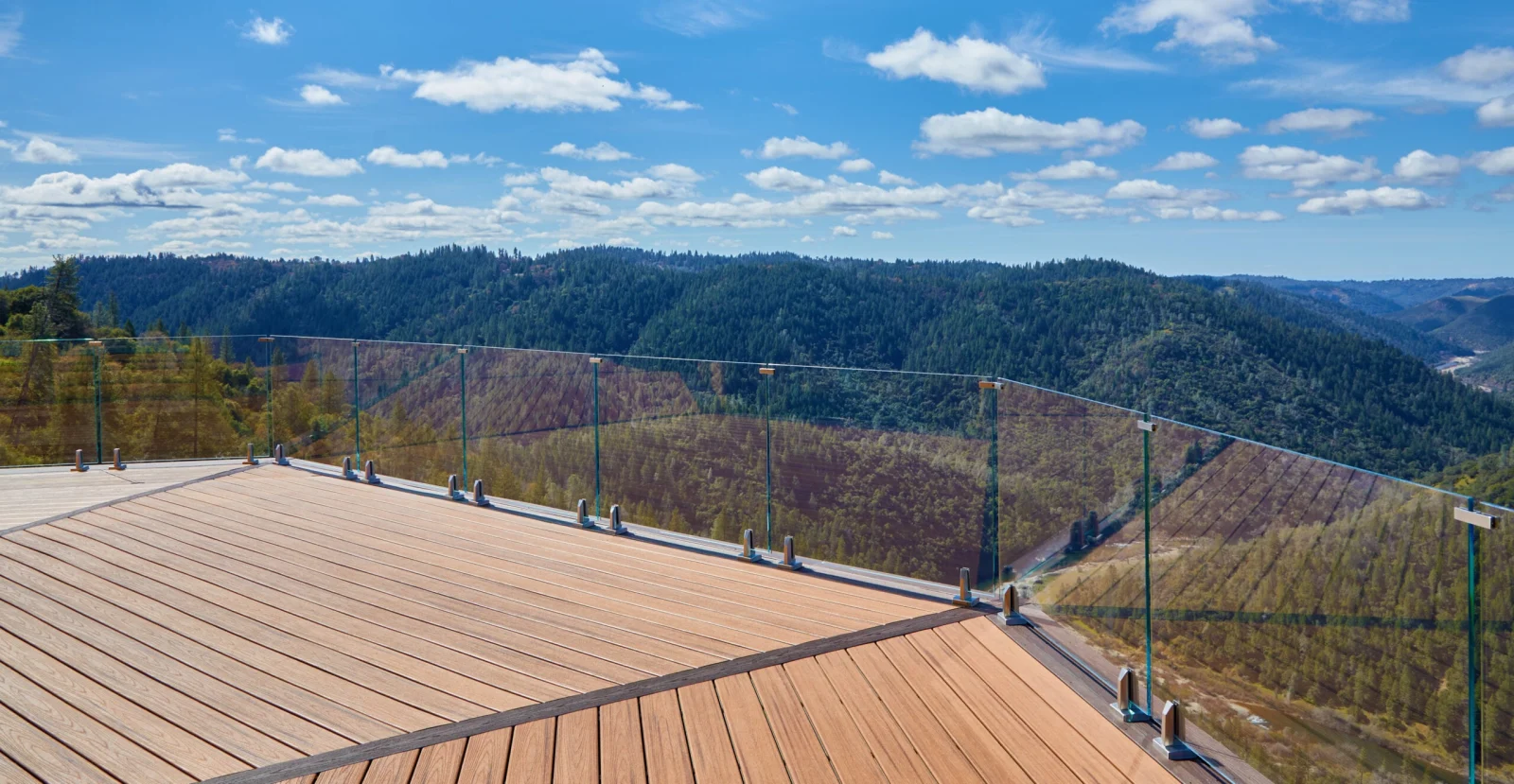 Panorama across the deck boards to hills framed by nearly invisible glass