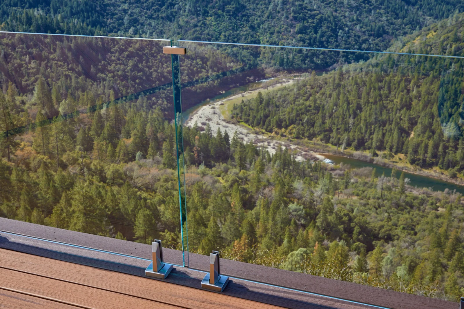 Glass panel and clamps in the foreground with a river winding far below