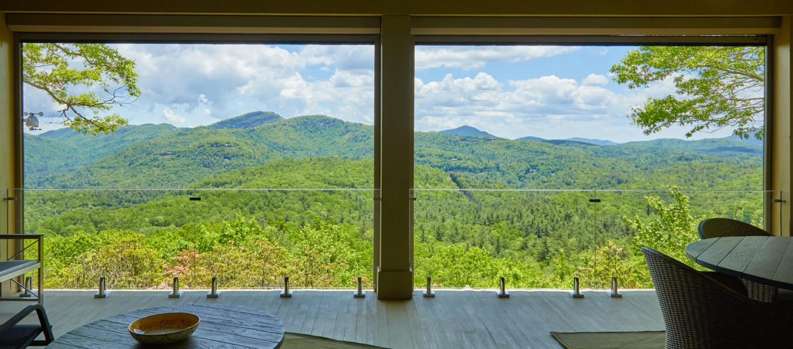 Mountain ridges framed by a wide opening, glass deck railing low across the view