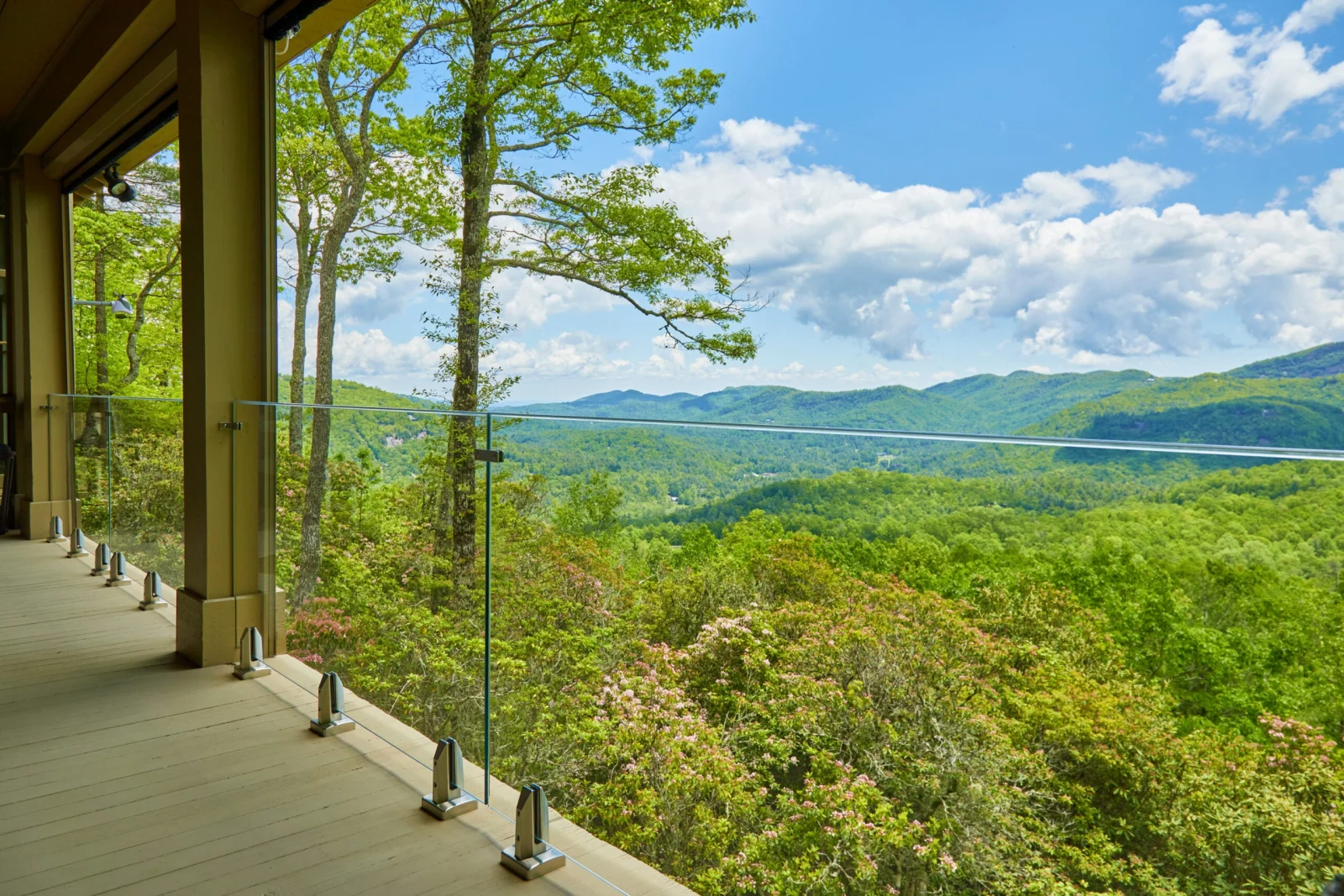 Covered porch edged in glass opening to layered mountains and treetops