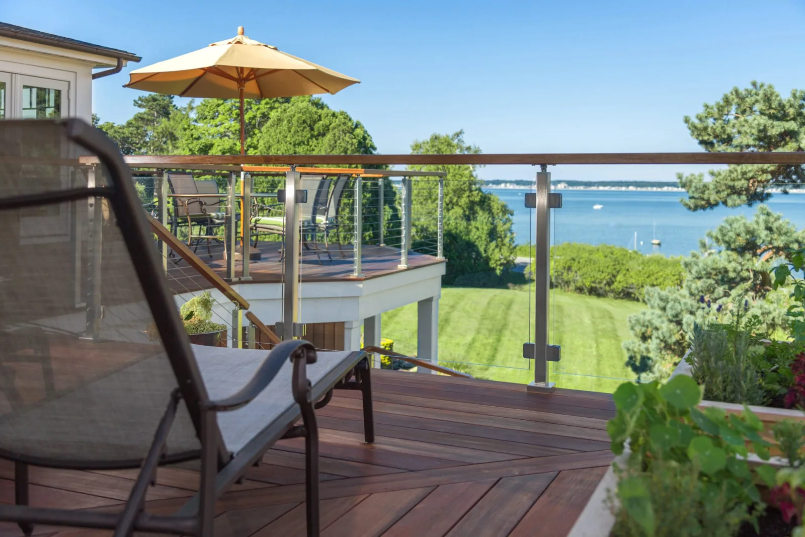 Deck overlooking open water with glass railing and wood top rail framing the view