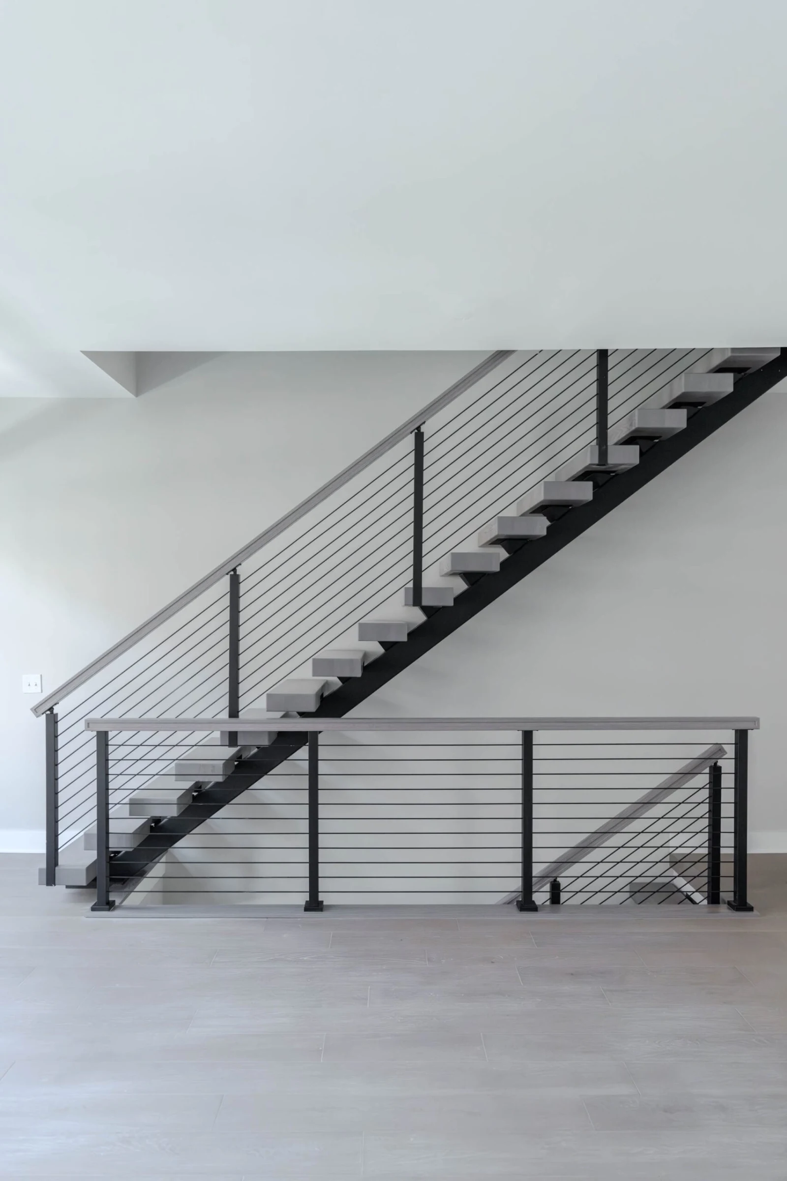 Straight-on view of a floating stair on a black center stringer with rod railing