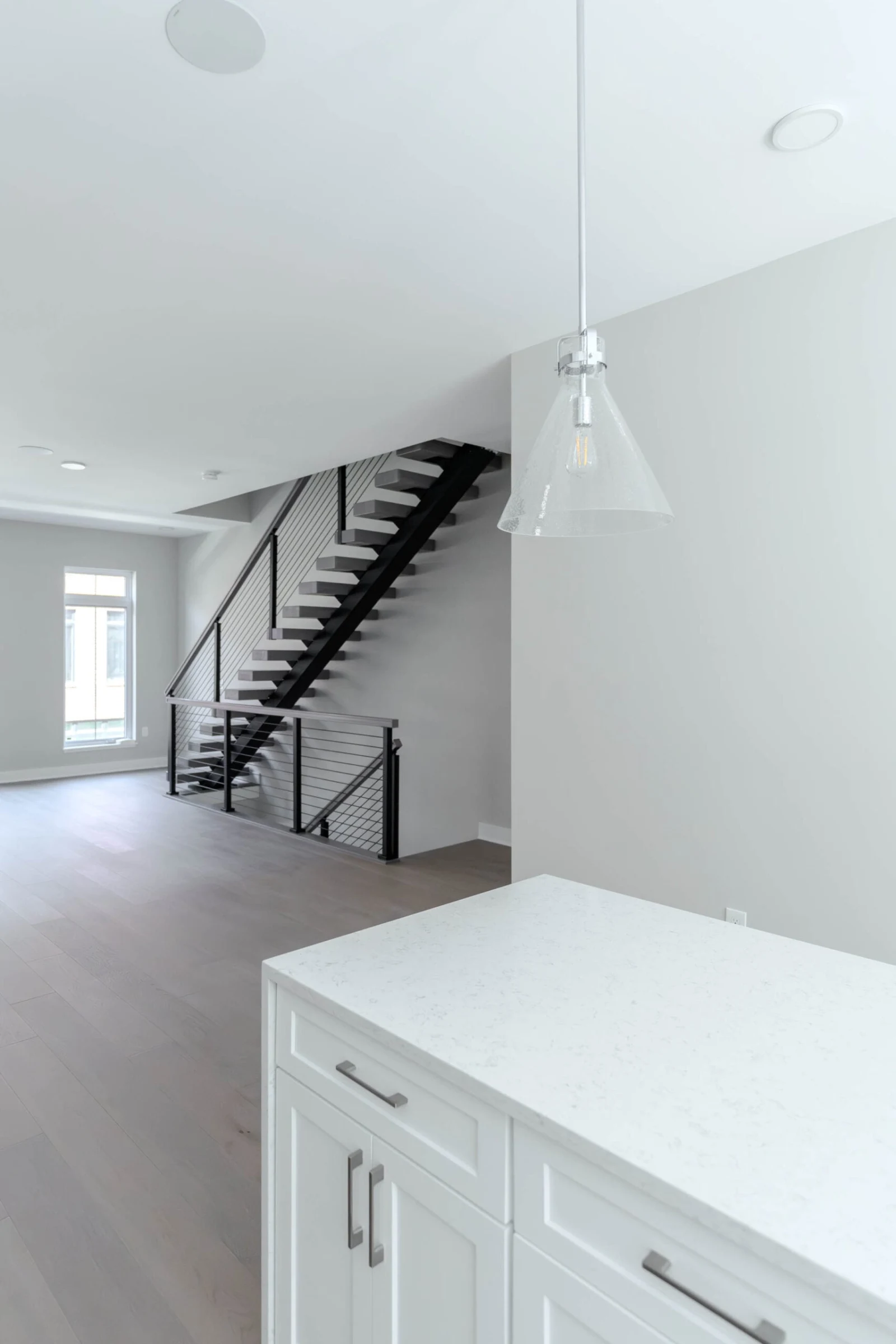 Kitchen counter in the foreground with the rod-railed stair rising in the background
