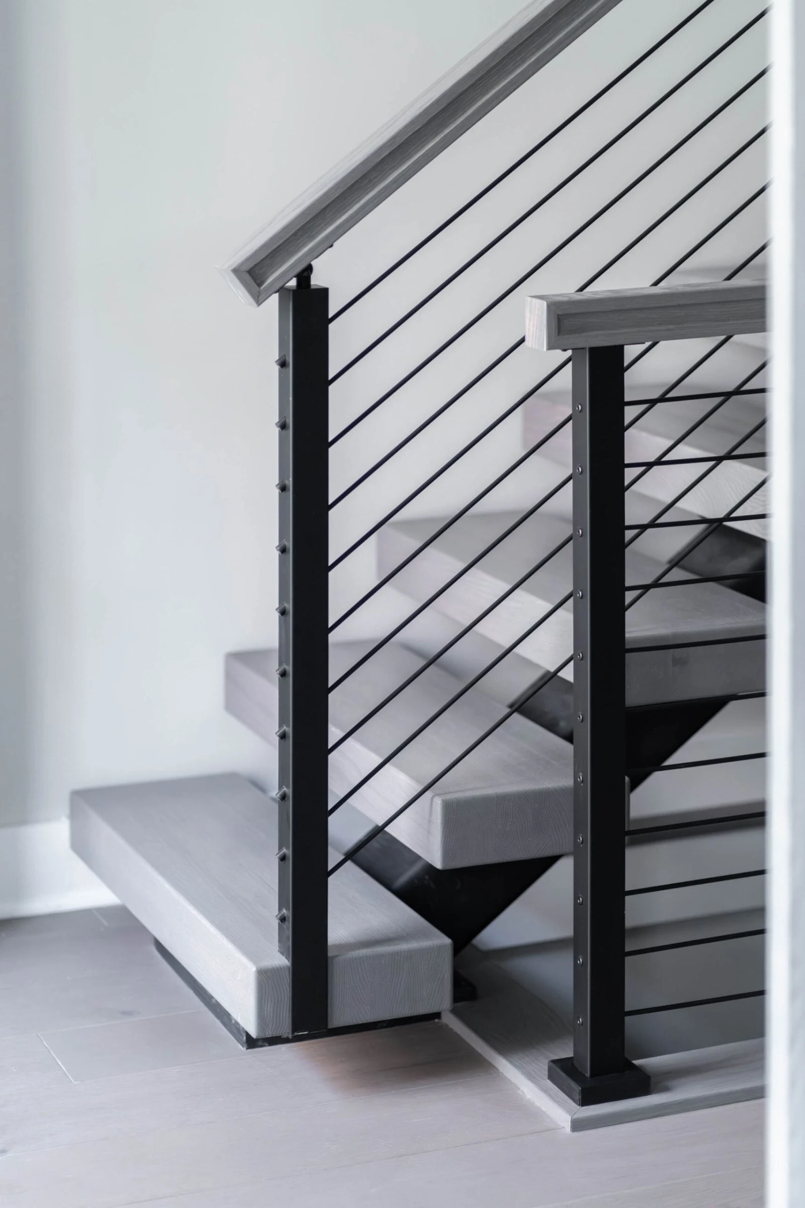 Bottom treads with two black posts, horizontal rods and a light wood top rail