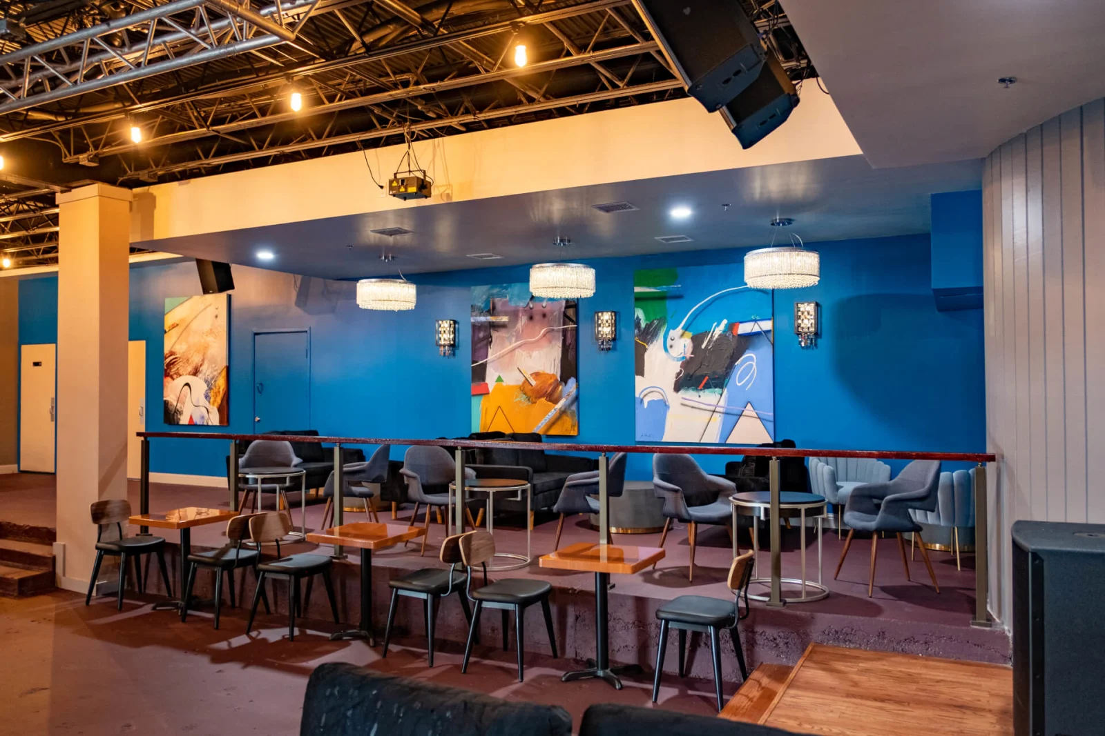 Blue-walled seating area with counter stools and a black guardrail closing the near edge