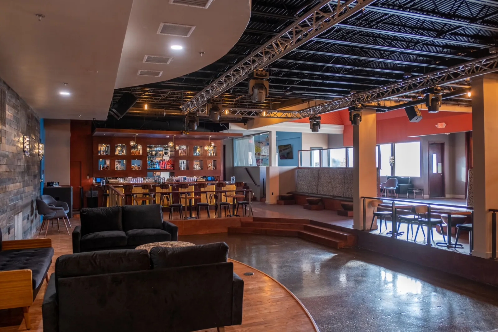 Back bar and lounge sofas viewed across a polished floor beside a railed step
