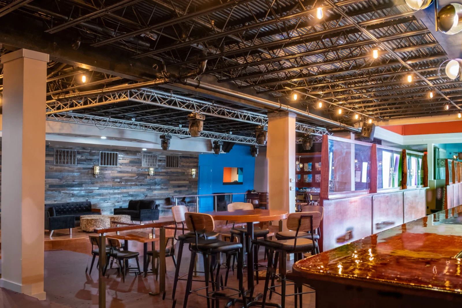 Pressed-metal ceiling and string lights above high-top tables beside a copper-topped bar
