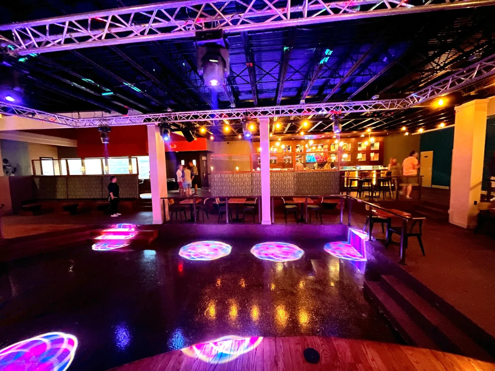 Dance floor washed in purple light with patterned projections and a railed upper level