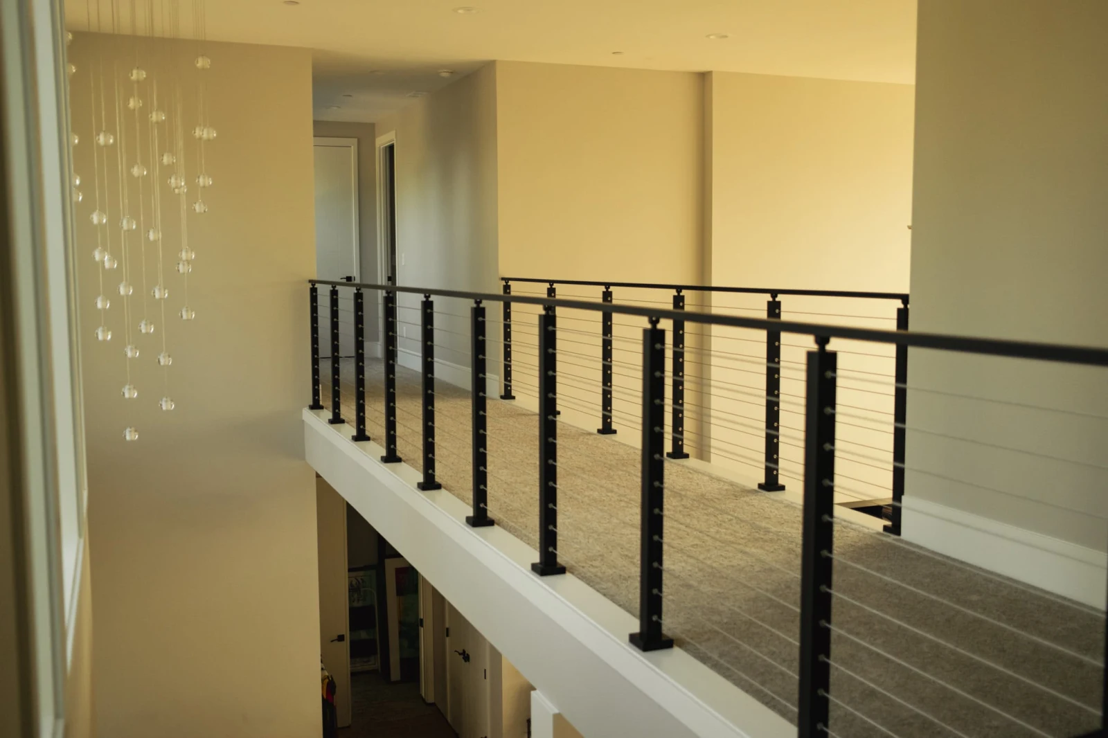 Carpeted catwalk edged with black posts and cable railing overlooking the room below