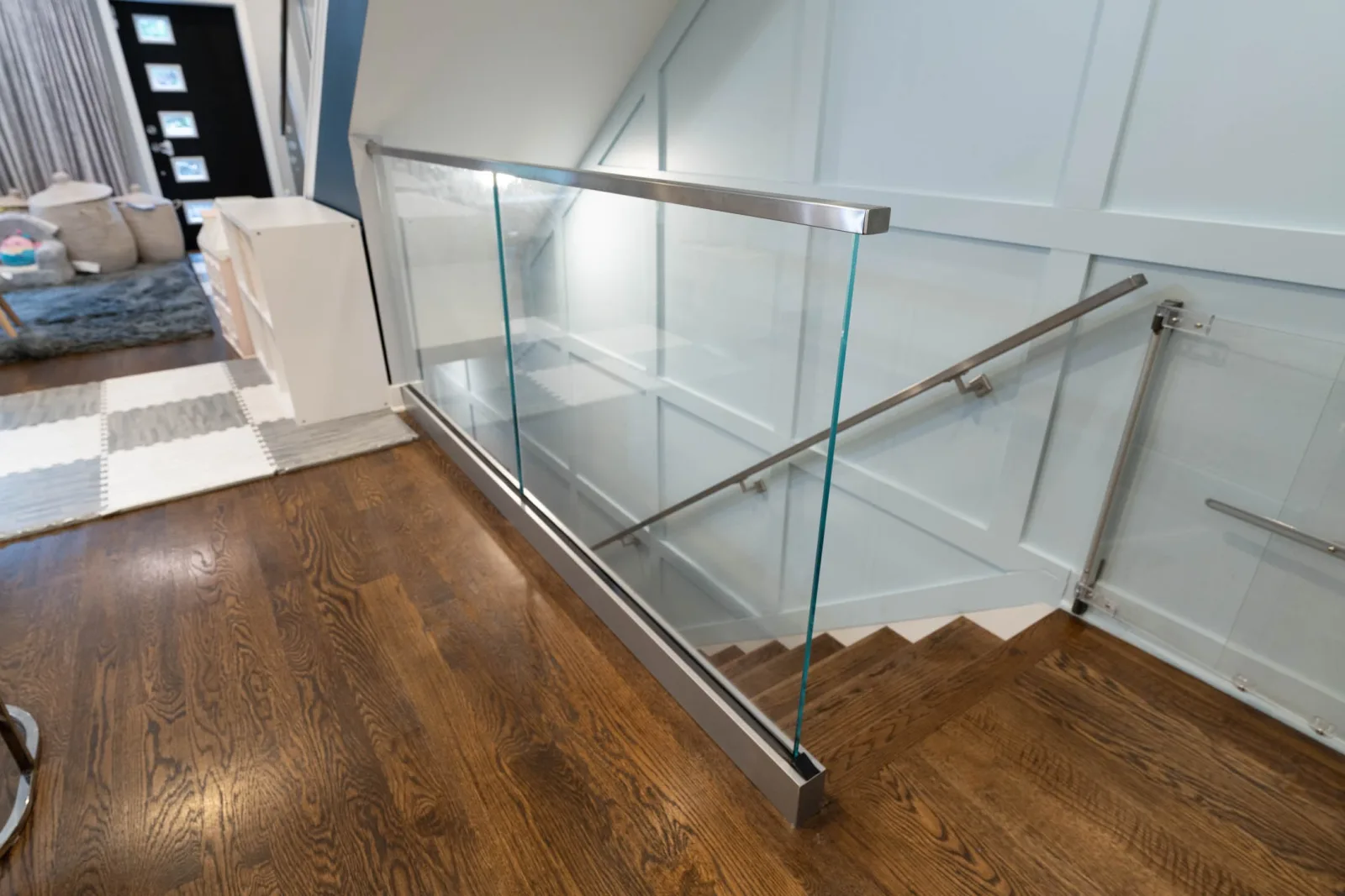 Stainless-capped glass railing along a stair opening with a matching wall-mounted handrail
