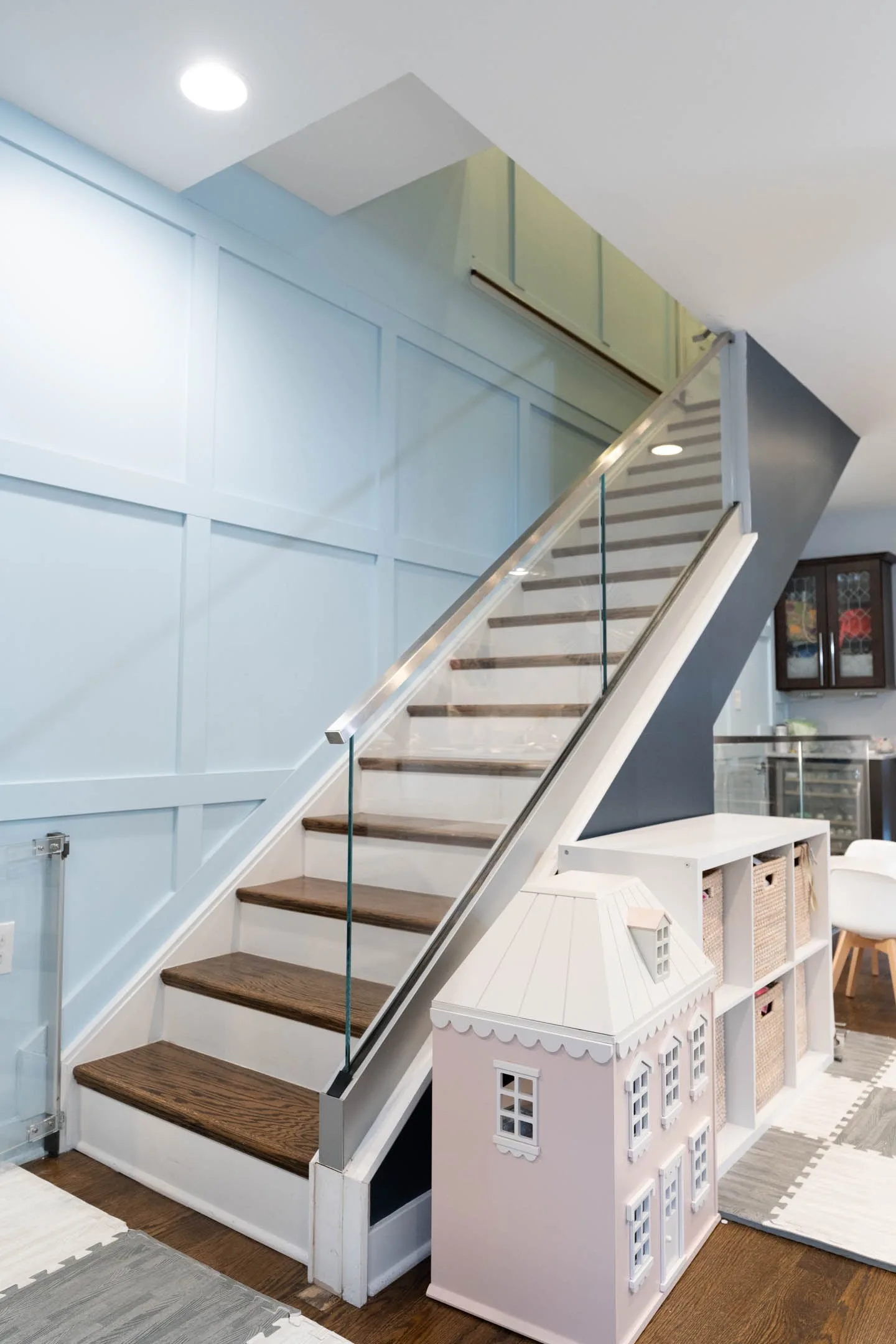 Straight stair of wood treads and white risers rising beside a glass guard panel