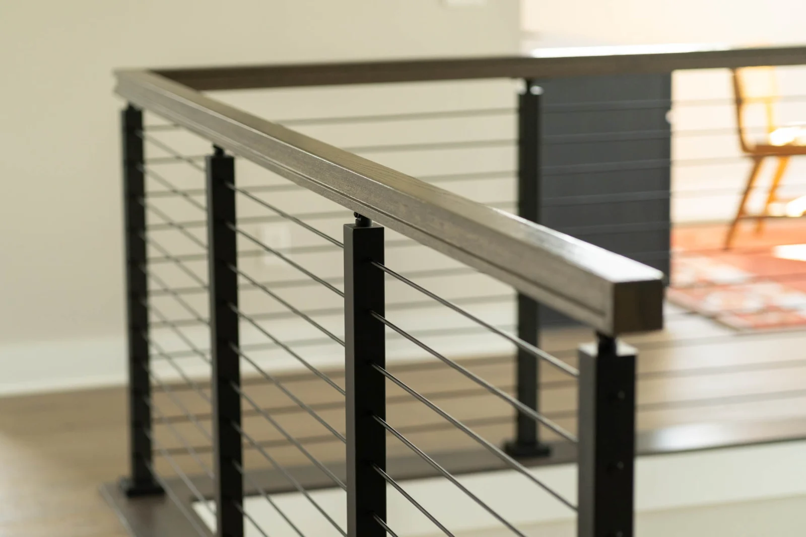 Rod railing run with wood top rail framing a dining area beyond