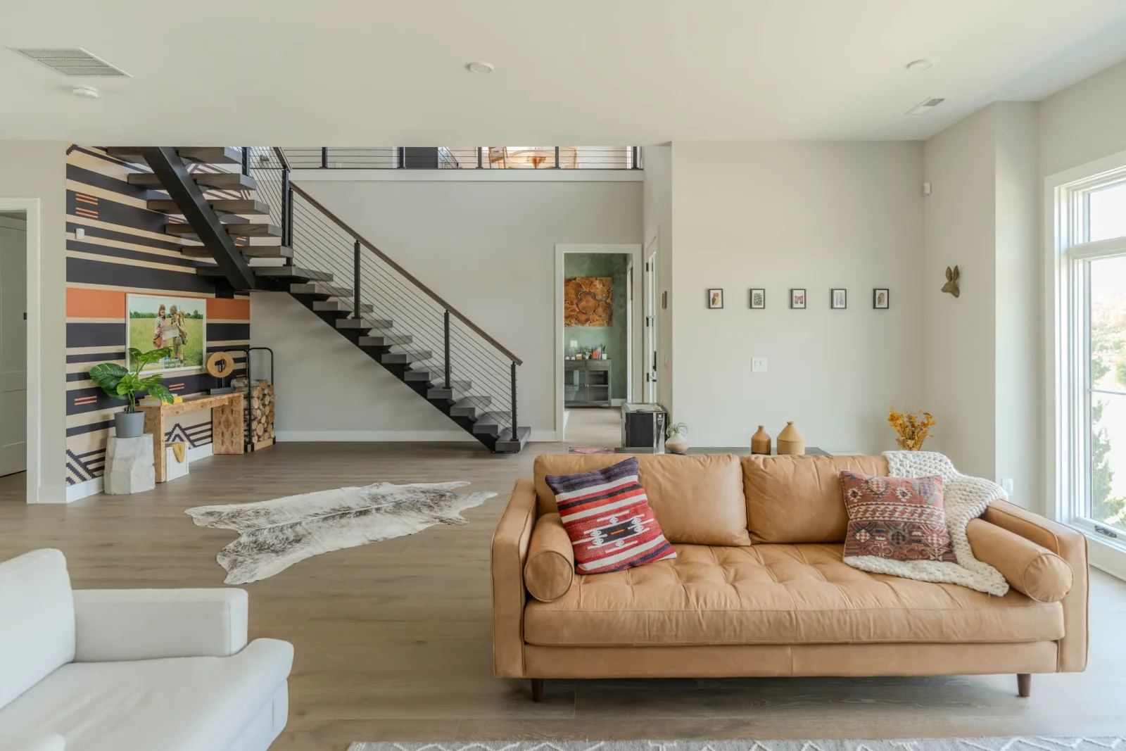 Living room with leather sofa and the stair rising along a striped accent wall