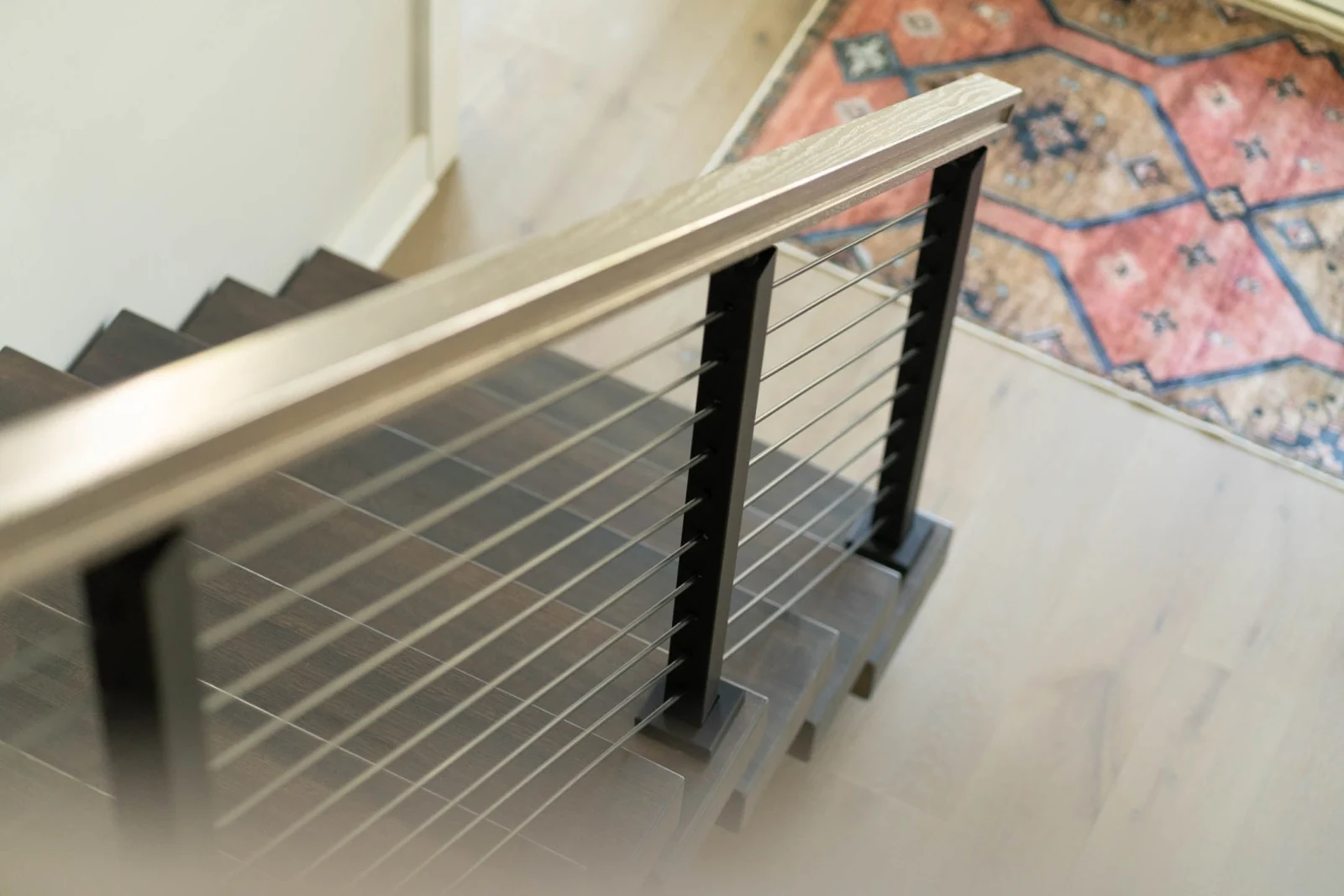 Looking down a landing run of rod railing toward a patterned rug below