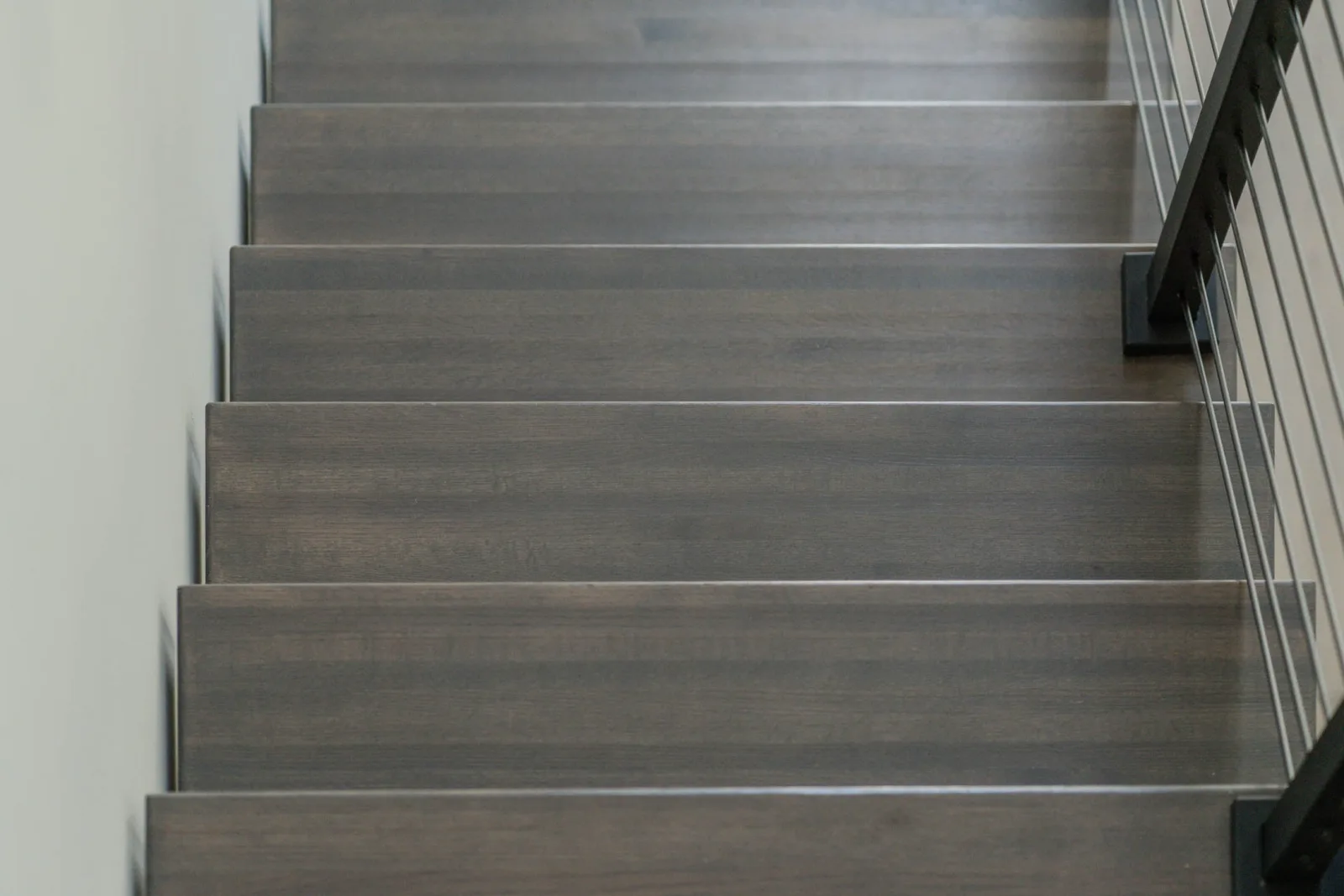 Close view up gray-stained treads with open risers beside the railing
