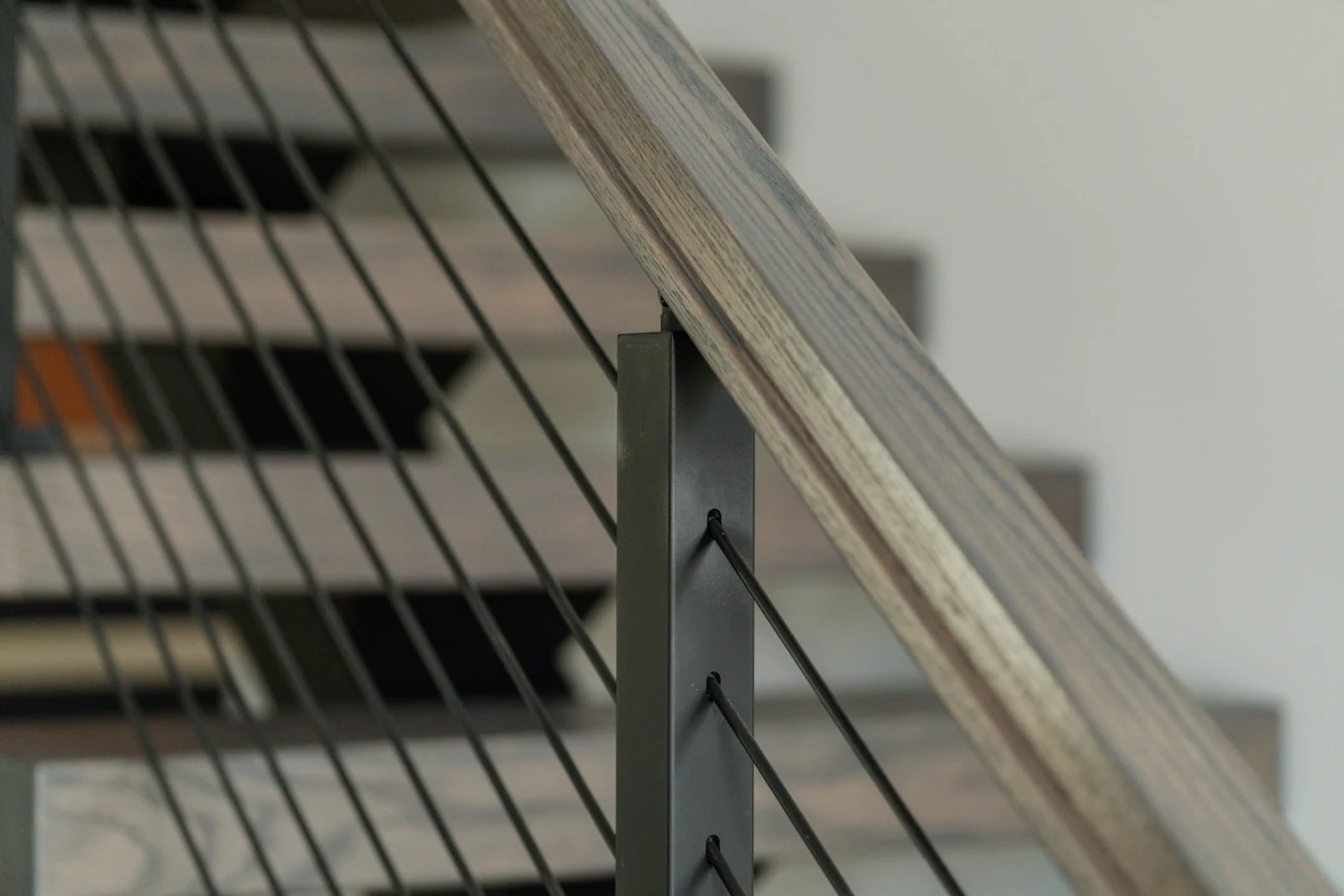 Detail of rods passing through a black post below a wood top rail