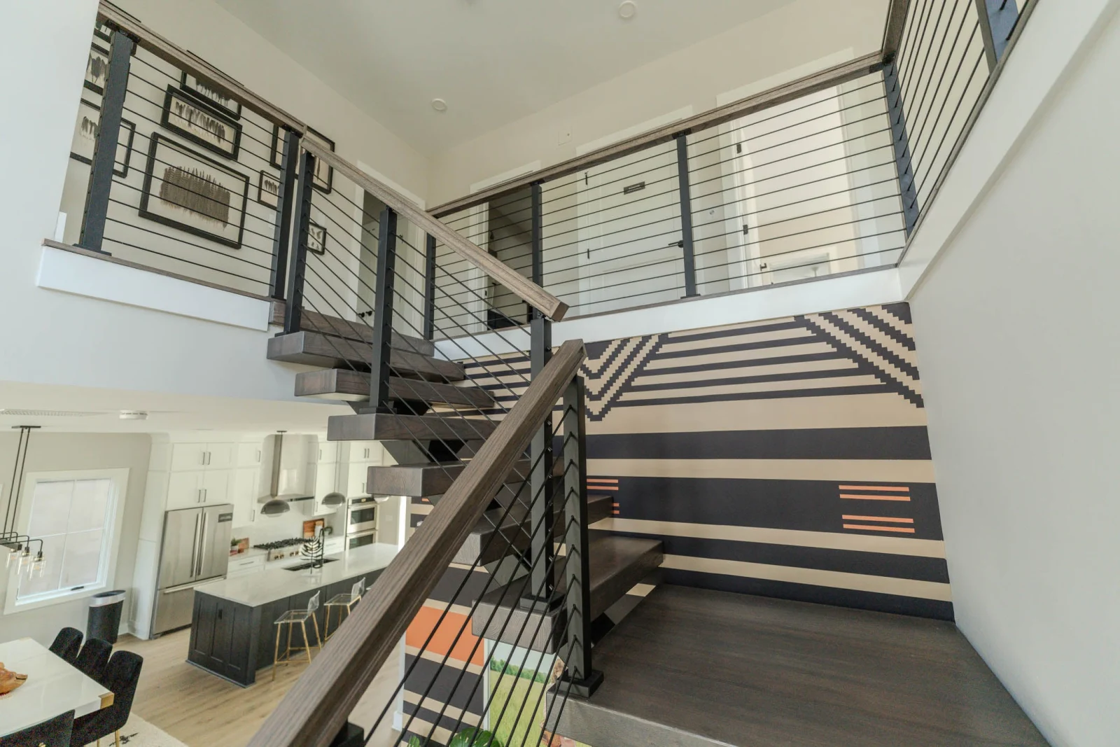 Two-story stairwell seen from below with rod railing wrapping the upper level