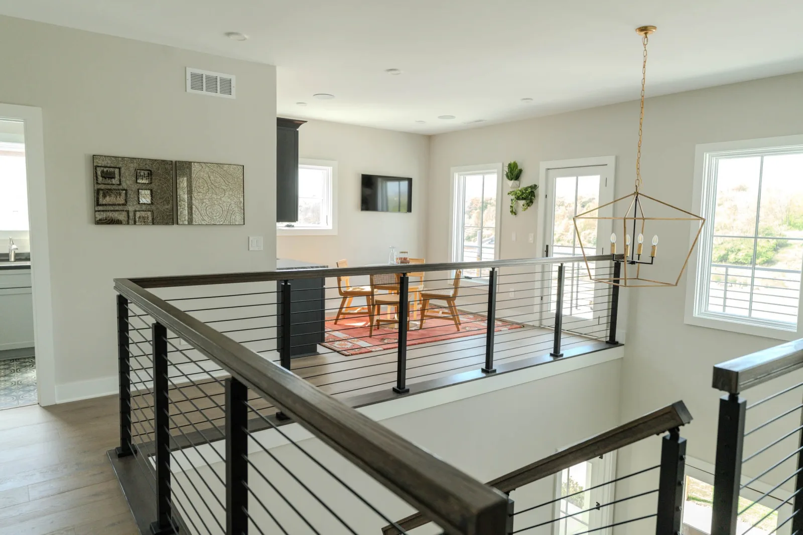 Upper landing rods and posts overlooking a dining table under a brass light
