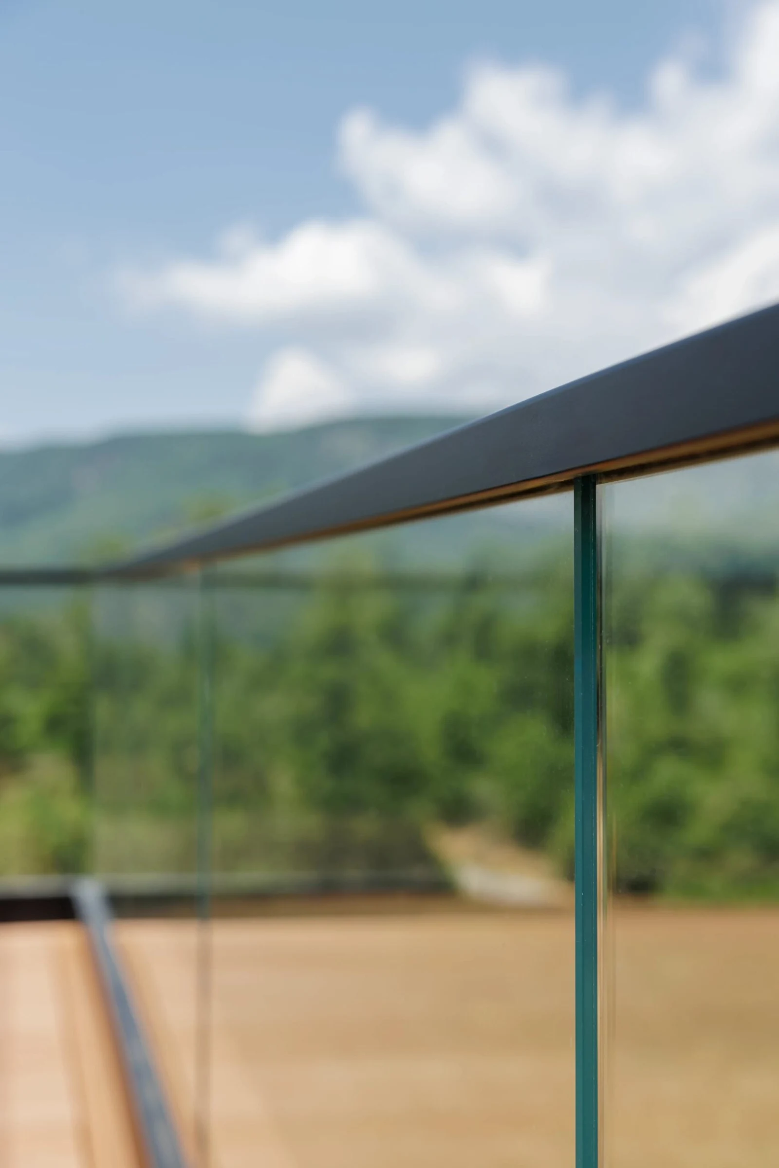 Close view of a glass panel edge and slim dark cap rail