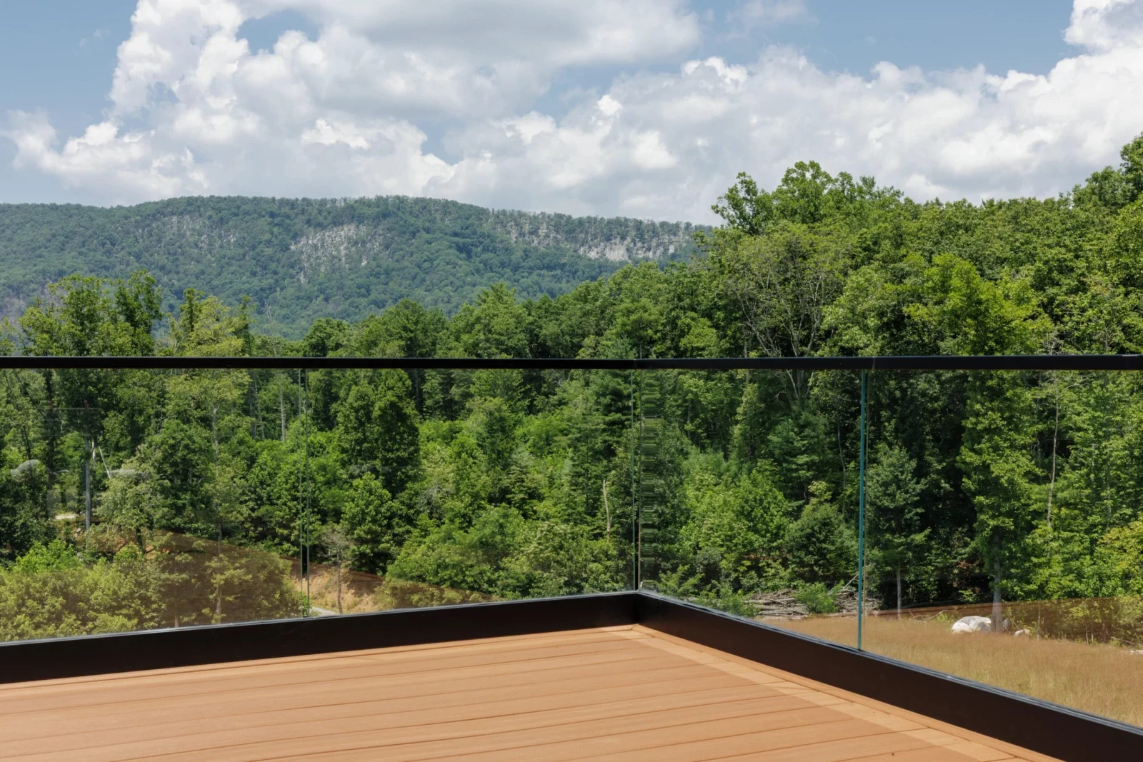 Deck corner framed by glass so the tree line stays unbroken