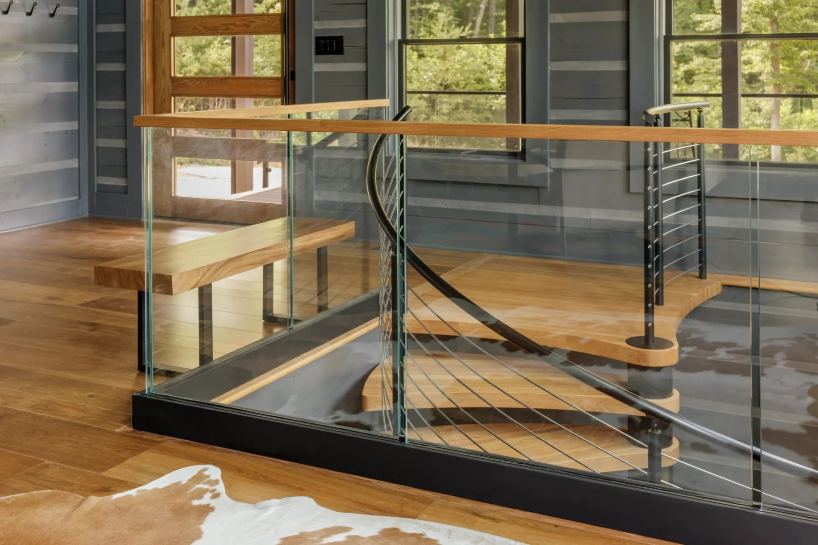 Cabin room where glass and cable railing guard the opening around the spiral