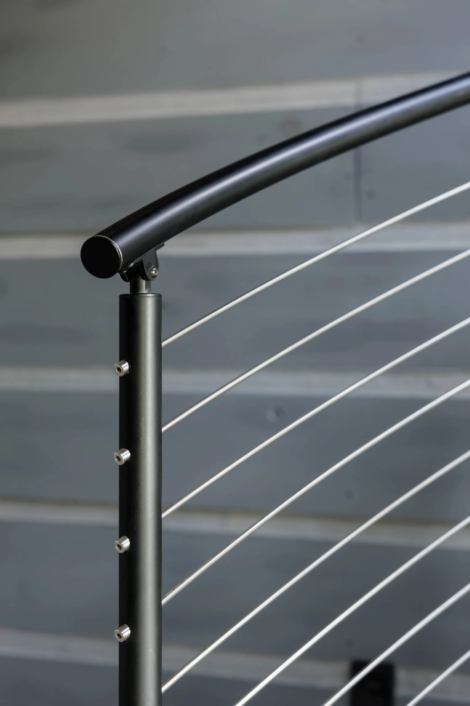 Detail of a post where the curved black handrail meets cable ends