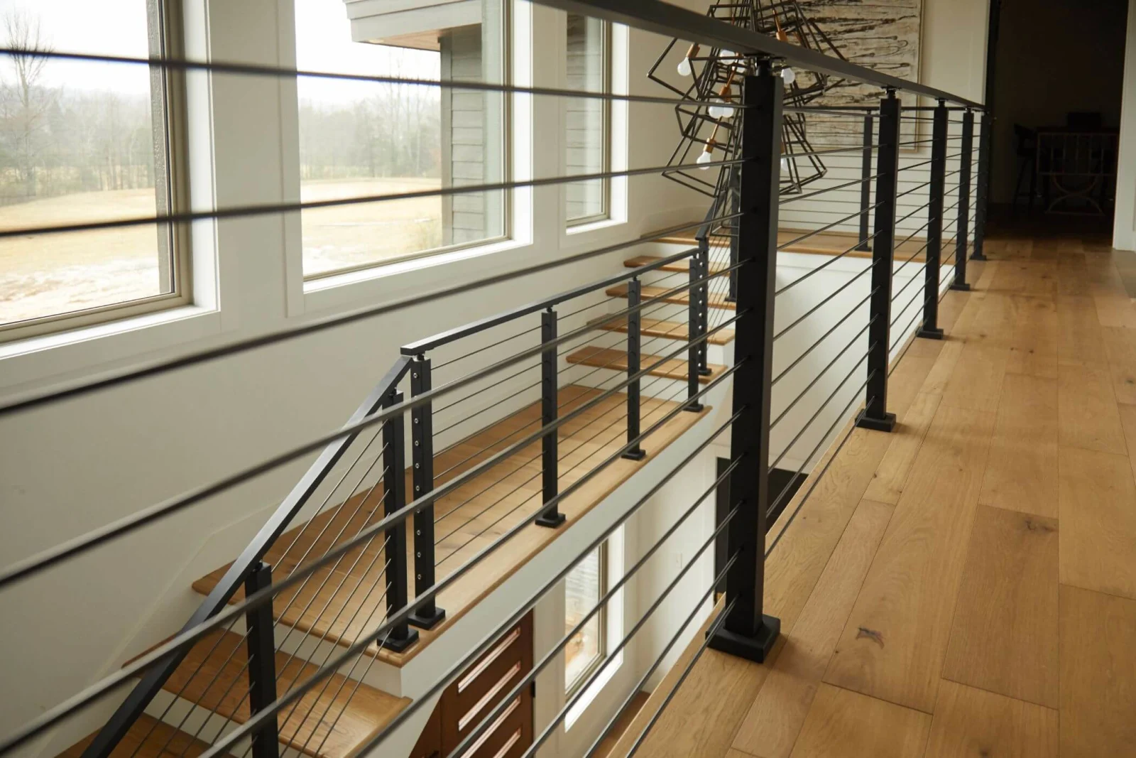 Long railing run tracing a window wall above wide plank flooring