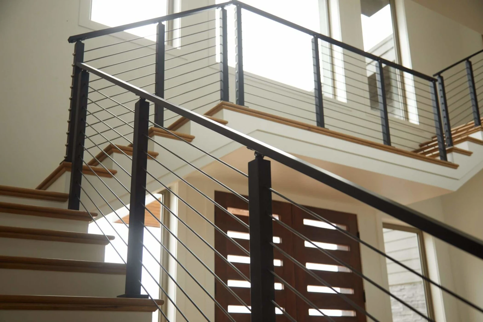 Looking up at railing runs on two levels against bright white walls