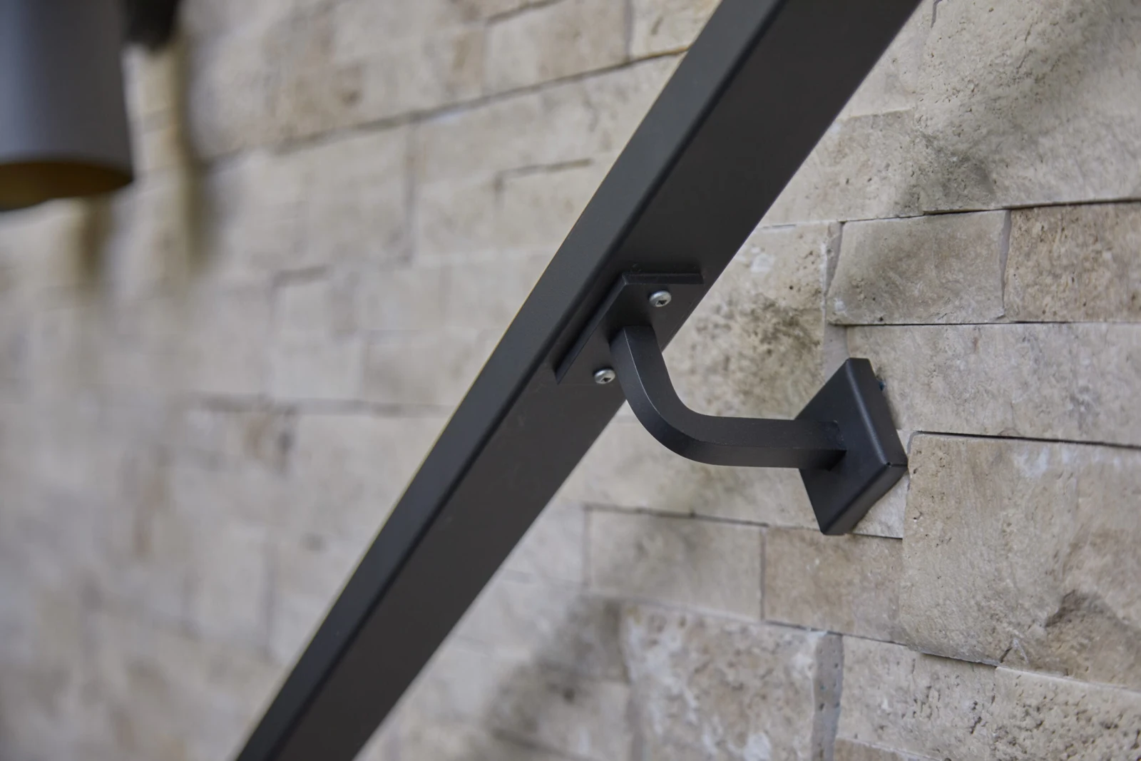 Close view of a handrail bracket anchored to a stacked stone wall