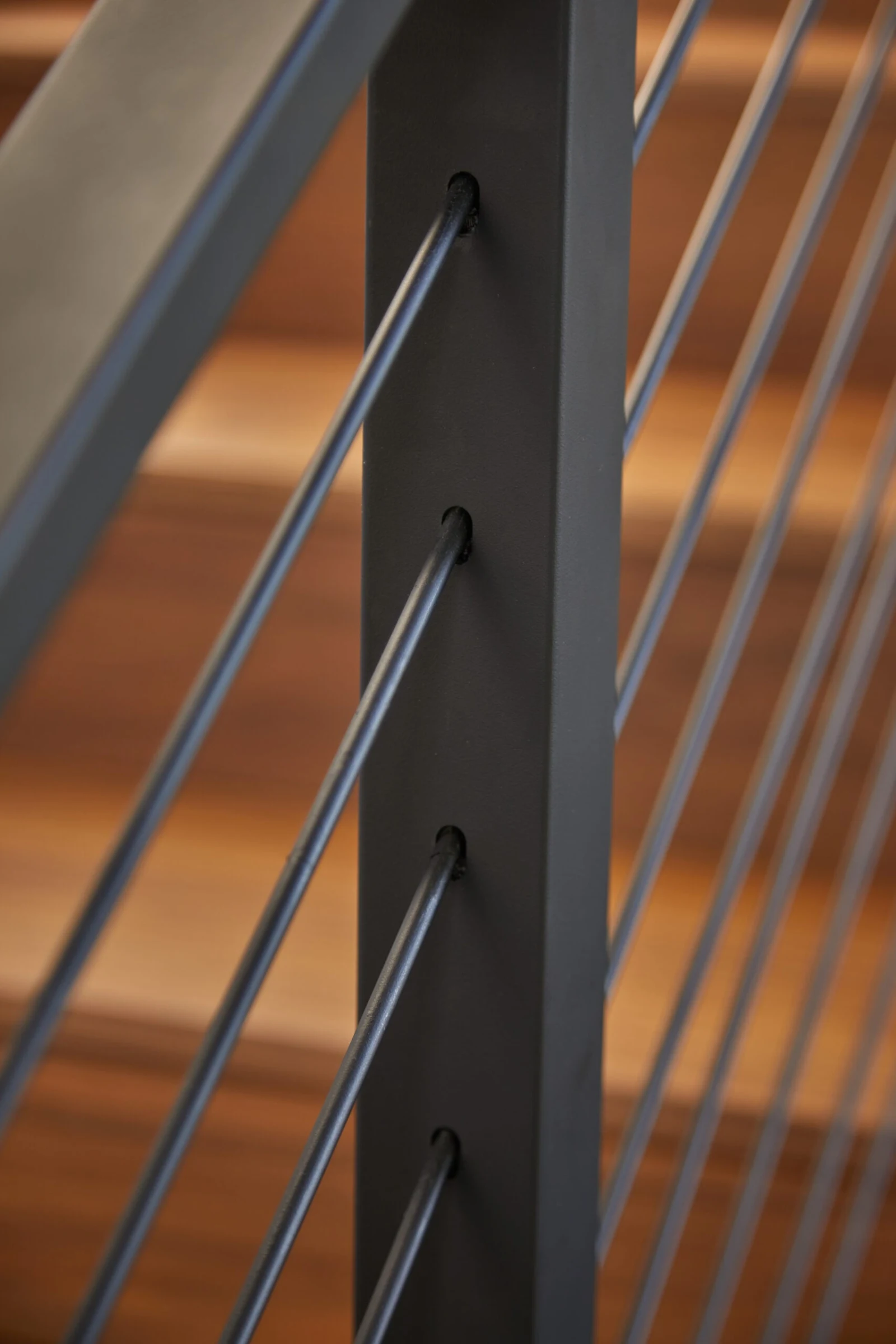 Rods seated through a black post with warm wood treads blurred behind