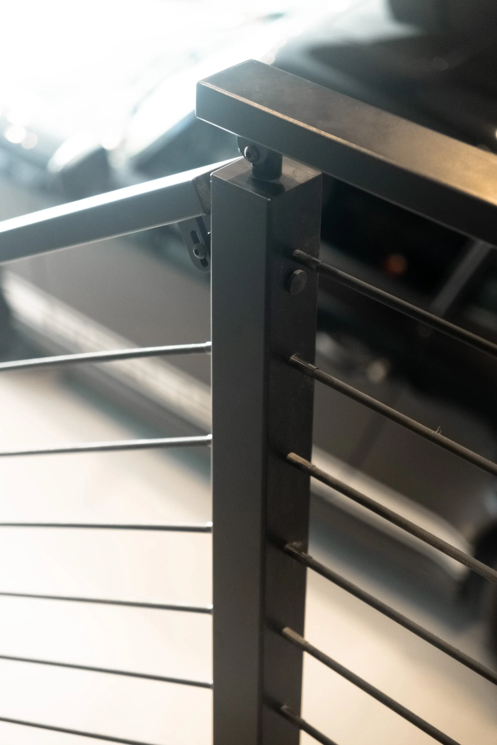 Detail of a black post cap where the flat top rail meets horizontal rods