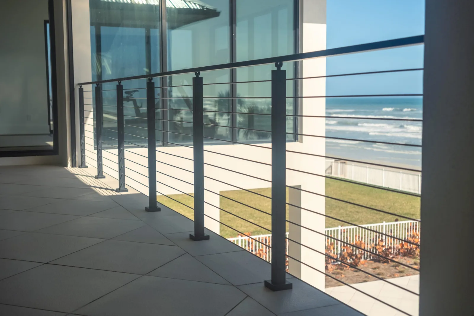 Black rod railing running along a tiled oceanfront balcony with open surf beyond