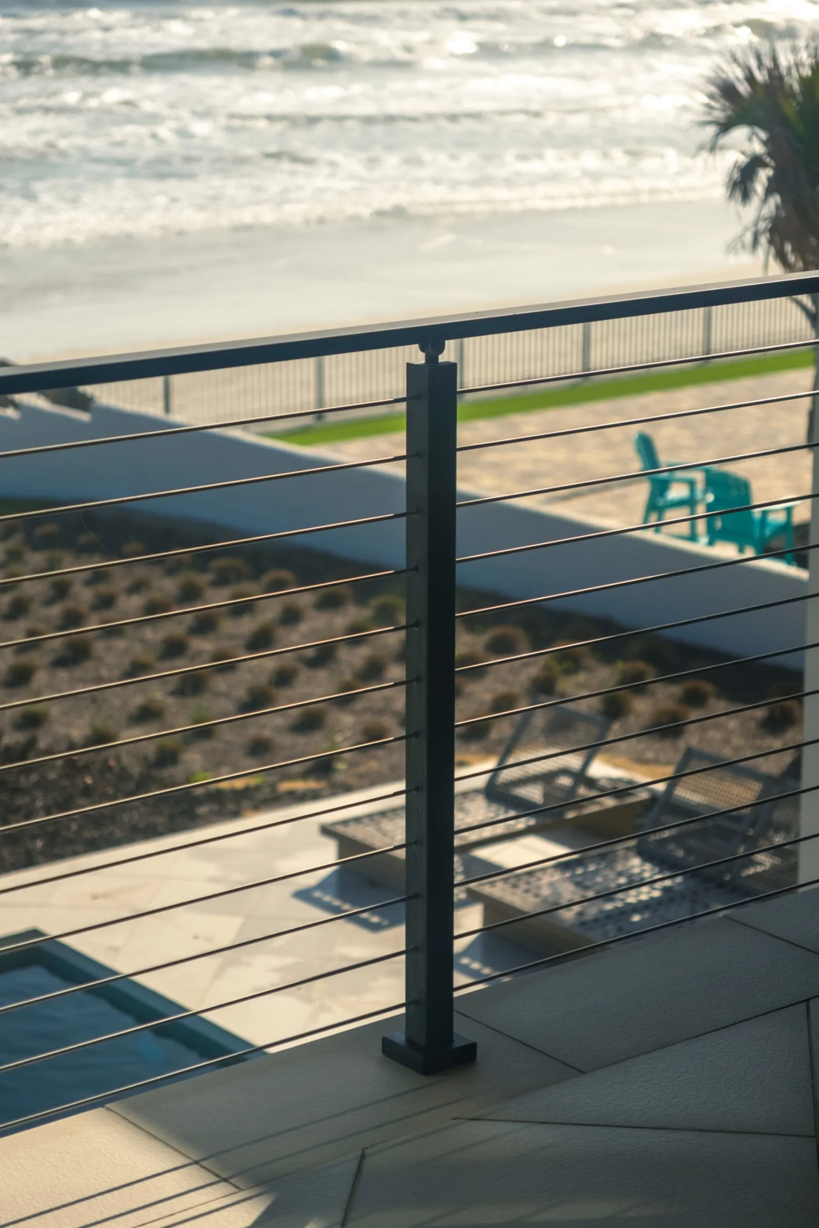 Looking down past a black post and rods to the boardwalk and shoreline below