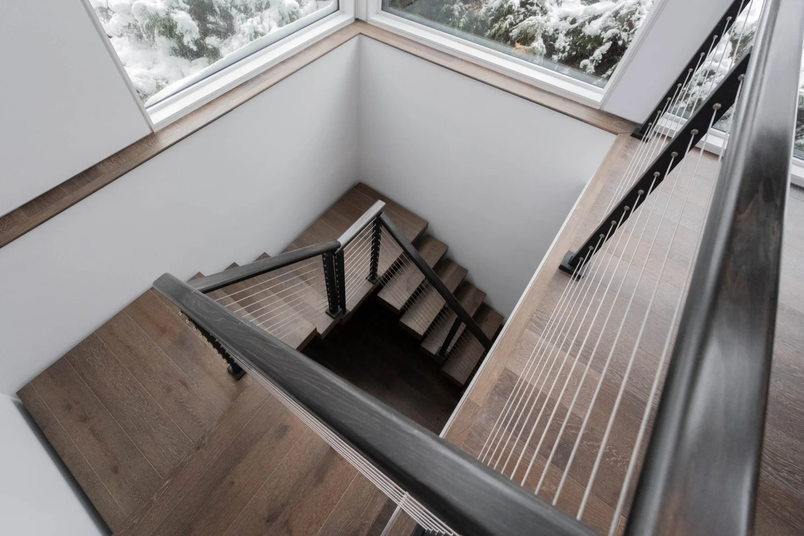Looking down a switchback stair framed by cable railing on both sides