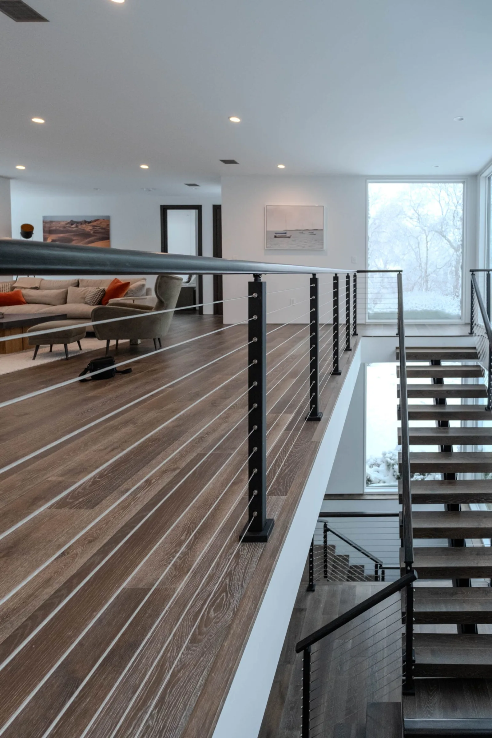 Loft overlook with black cable railing above an open stair and living area