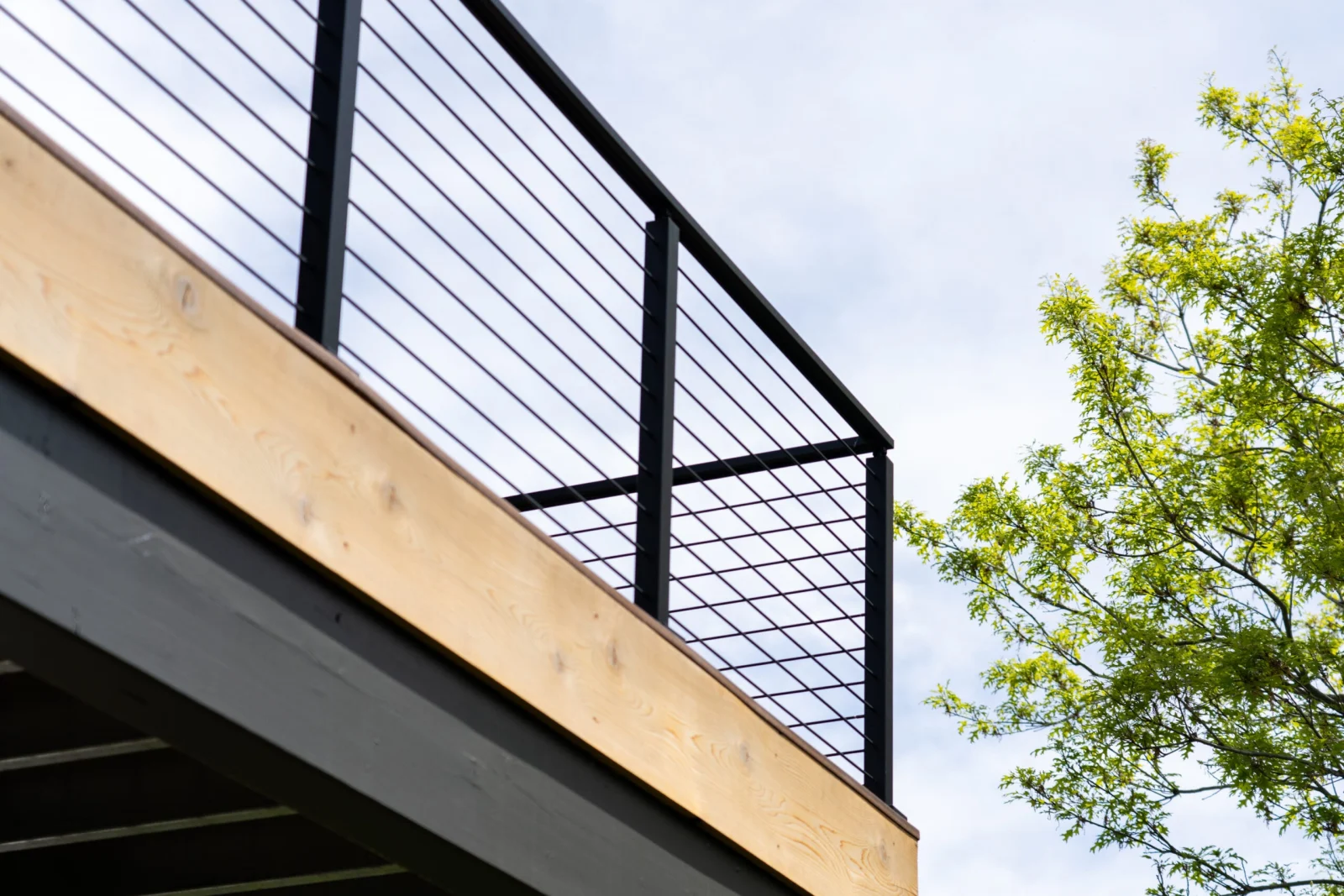 Black rod railing on an elevated deck seen from below against open sky