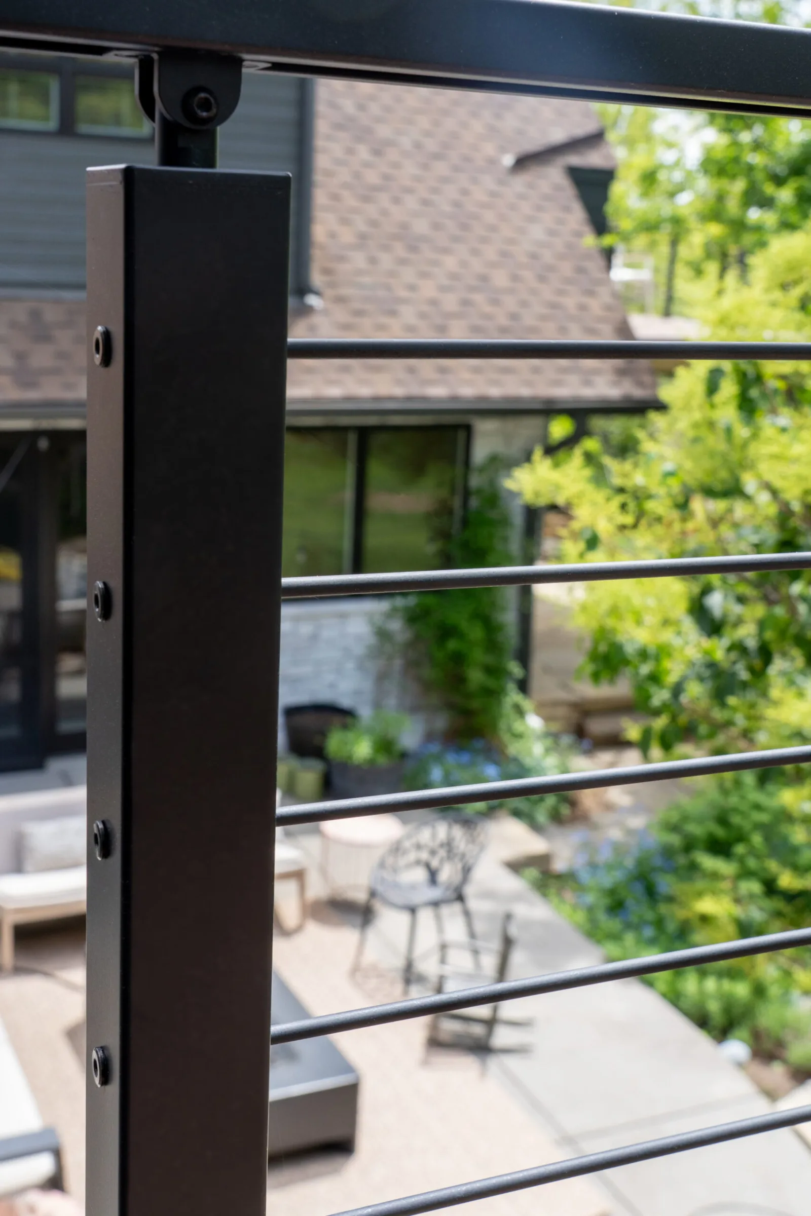Close black post threaded with rods overlooking a paved patio and garden