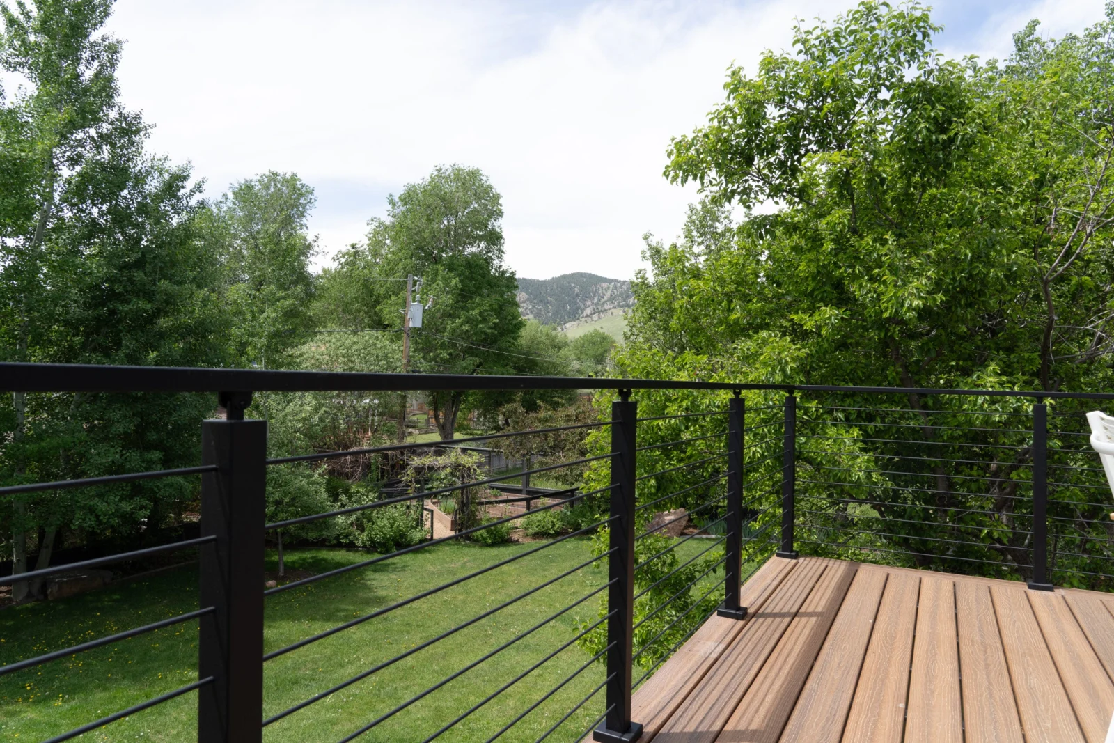 Rod railing wrapping a deck corner with foothills rising past the treetops