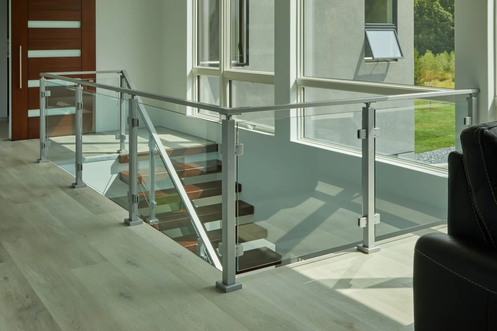 Overlook railing of glass panels and silver posts above a stair descending past the entry