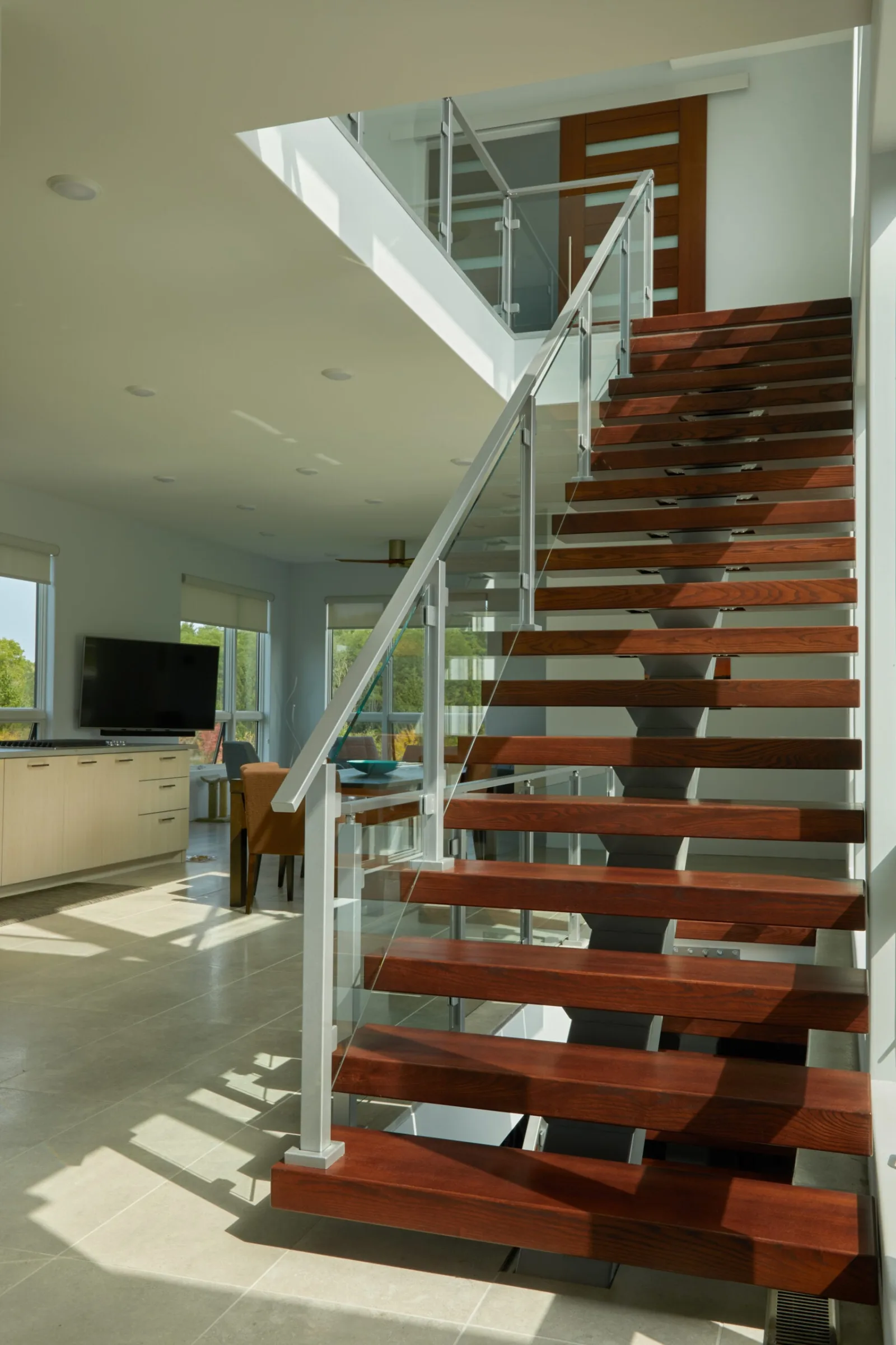 View up the flight past glass railing toward the kitchen and living area