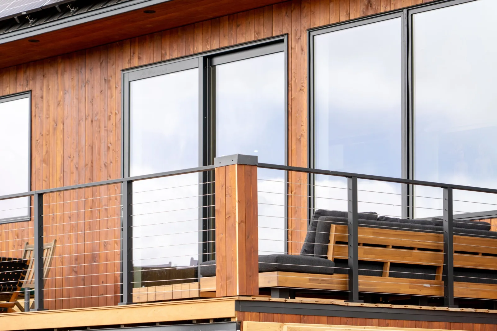 Cable railing along the deck of a wood-sided home with built-in bench seating