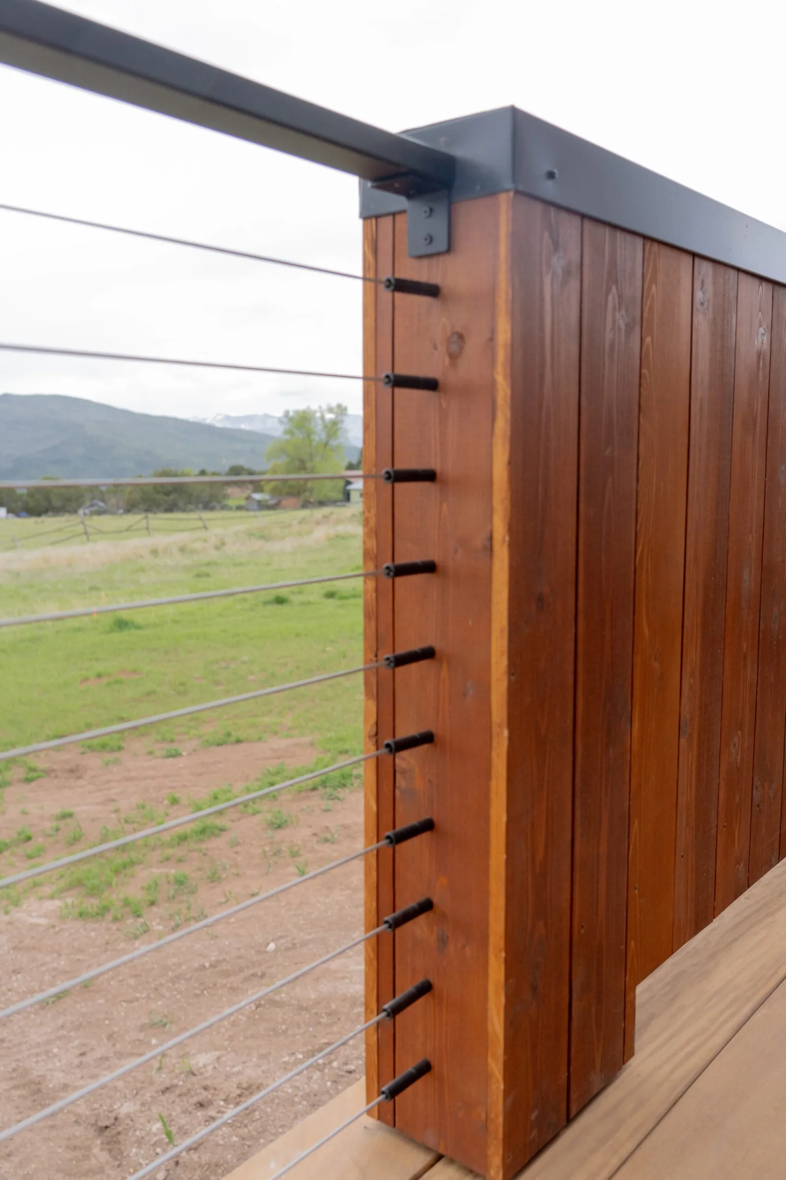 Detail of a wood post with black cable fittings under a metal top rail